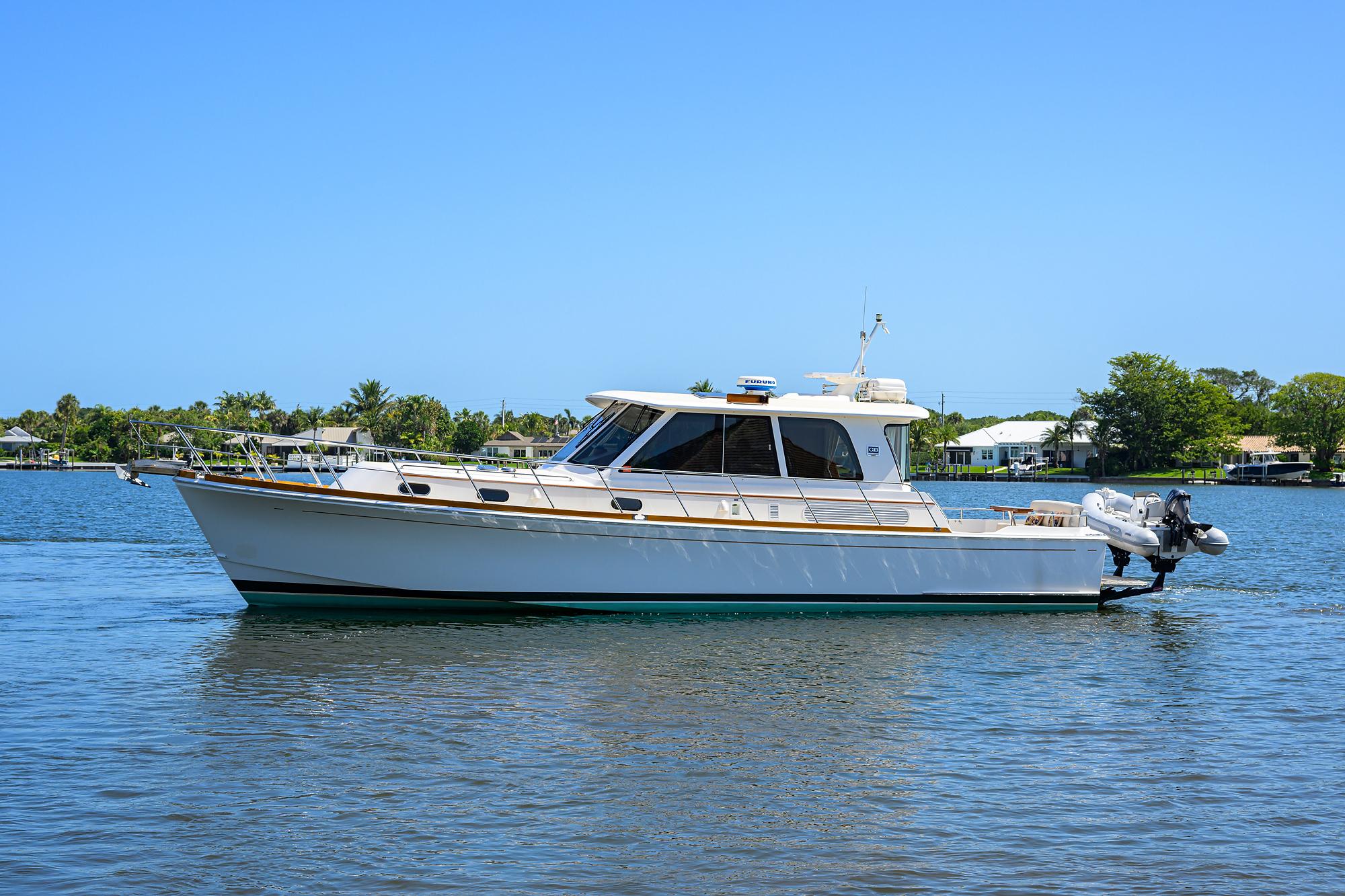 2014 Grand Banks 46 Eastbay SX yacht on calm water, clear sky background.
