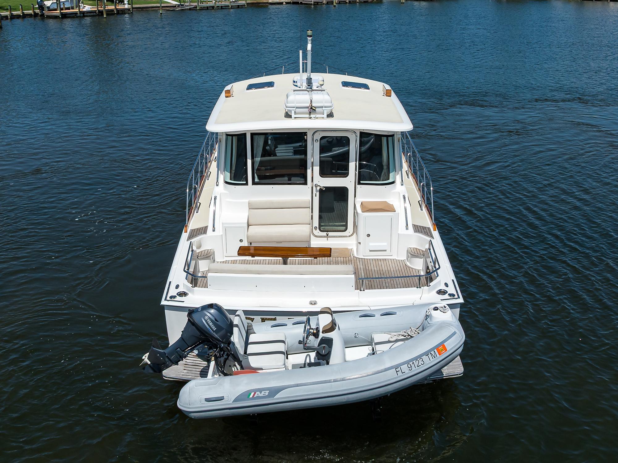 2014 Grand Banks 46 Eastbay SX yacht with dinghy on calm water.