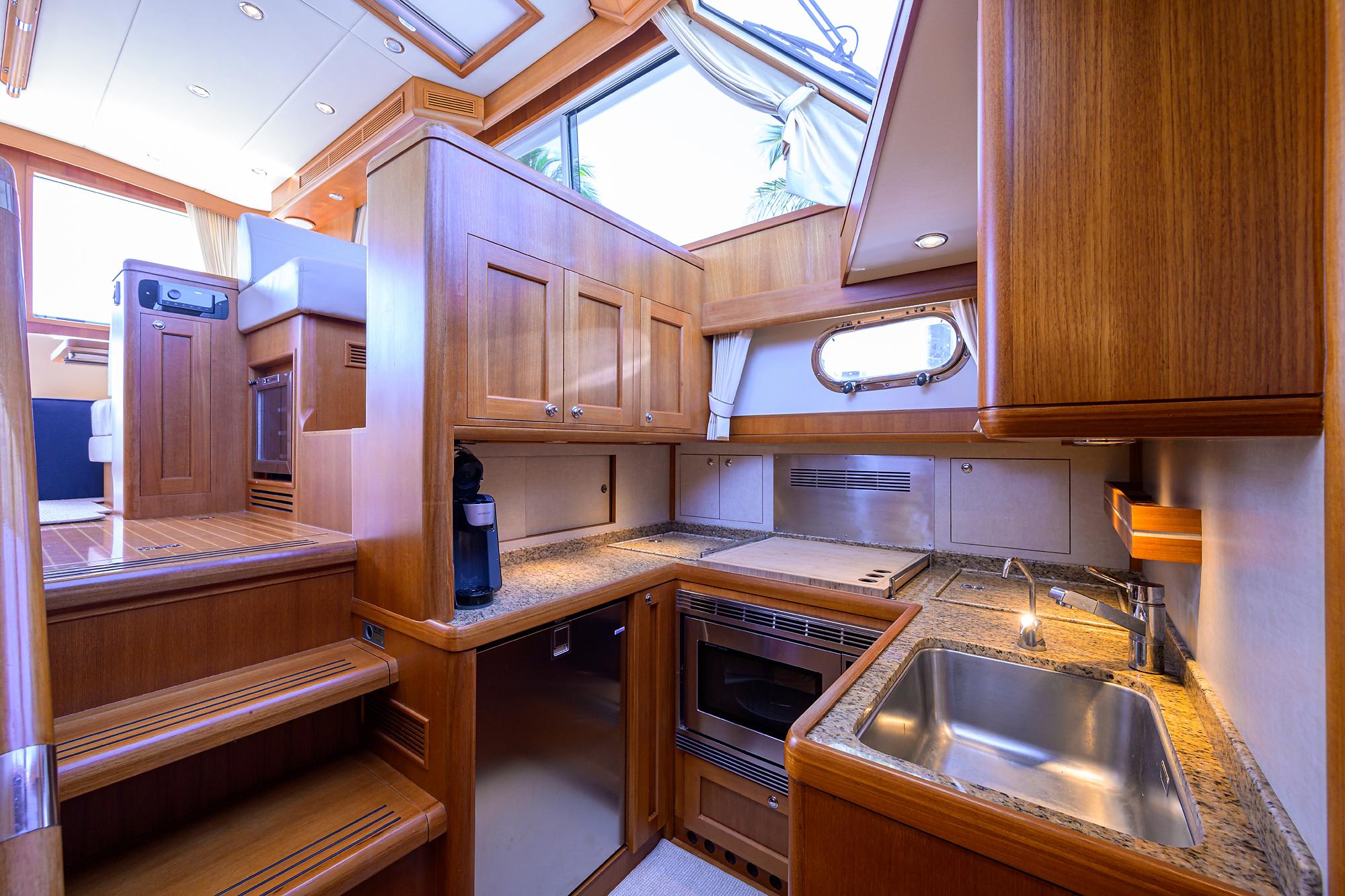 Luxurious 2014 Grand Banks 46 Eastbay SX yacht interior with modern kitchen and wooden cabinetry.