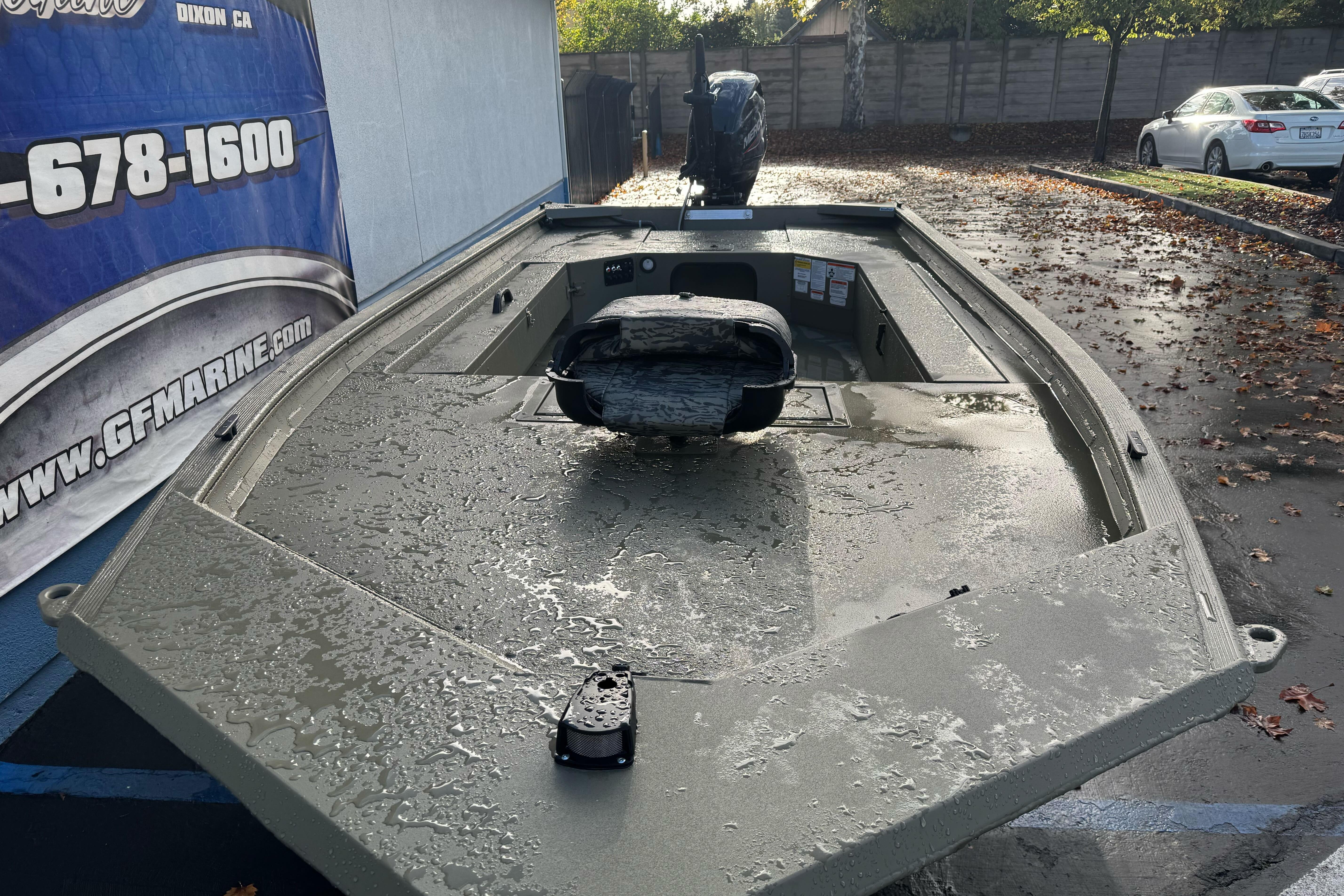 2026 Tracker Grizzly 1654 T Sportsman boat, wet surface, parked outdoors near a marine shop.