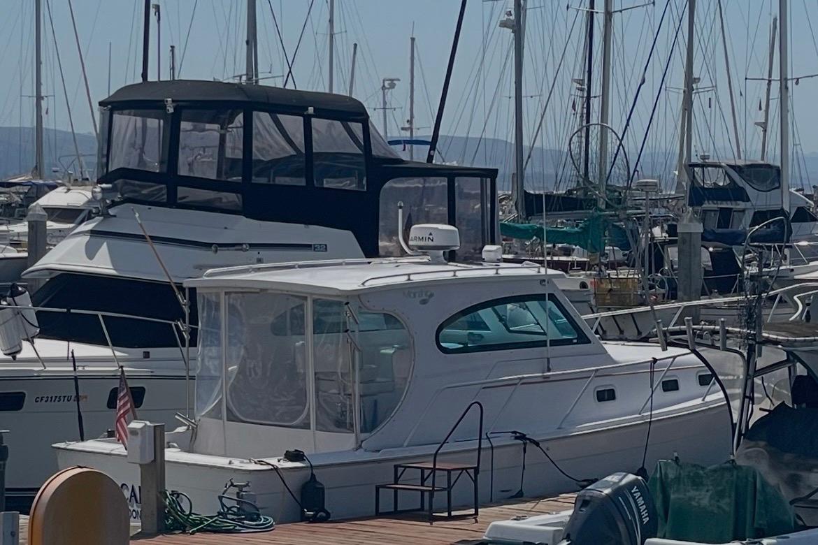 1999 Mainship Pilot 30 docked at a marina with other boats.