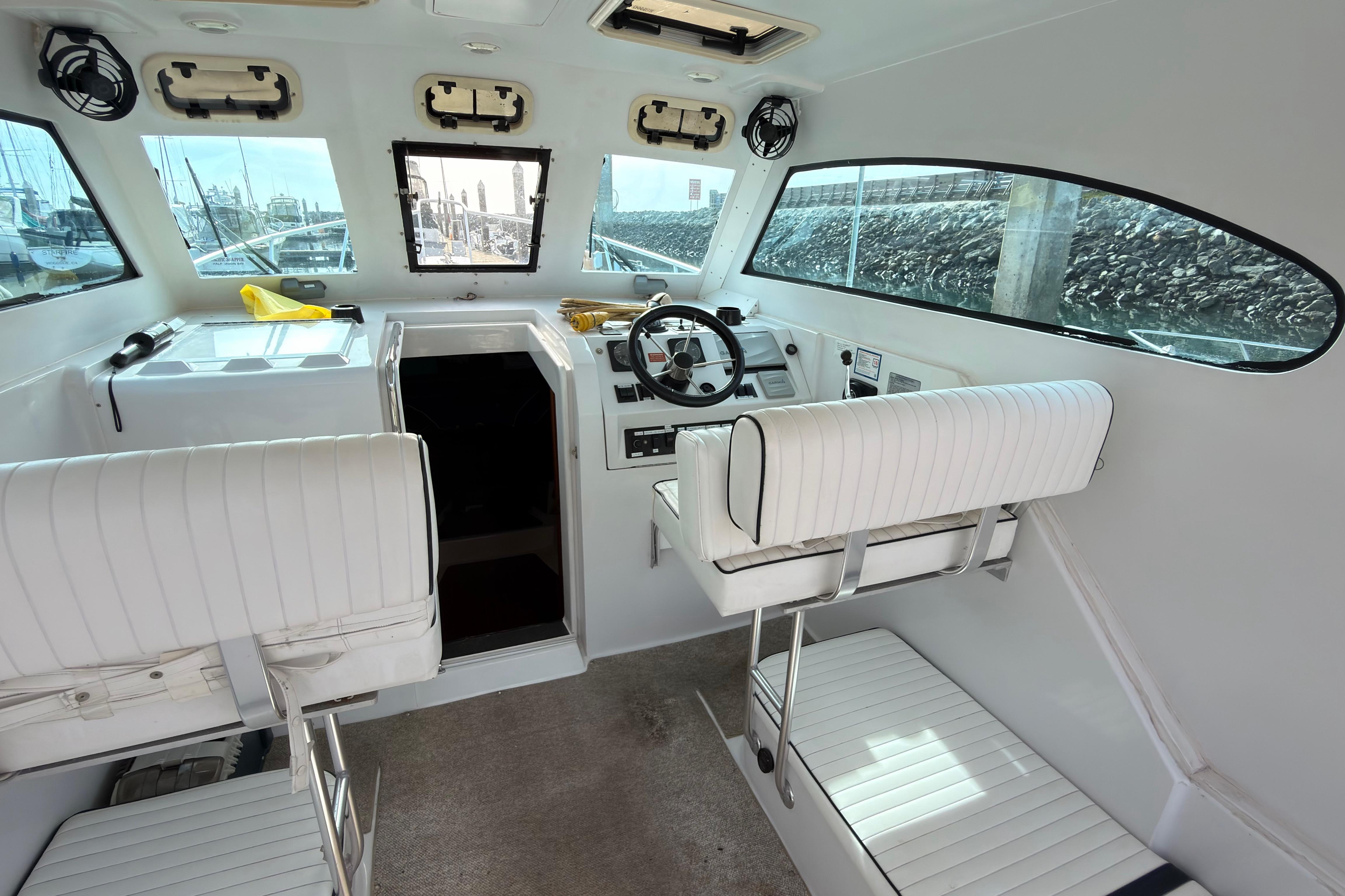 1999 Mainship Pilot 30 interior with white seating and steering wheel, docked at marina.