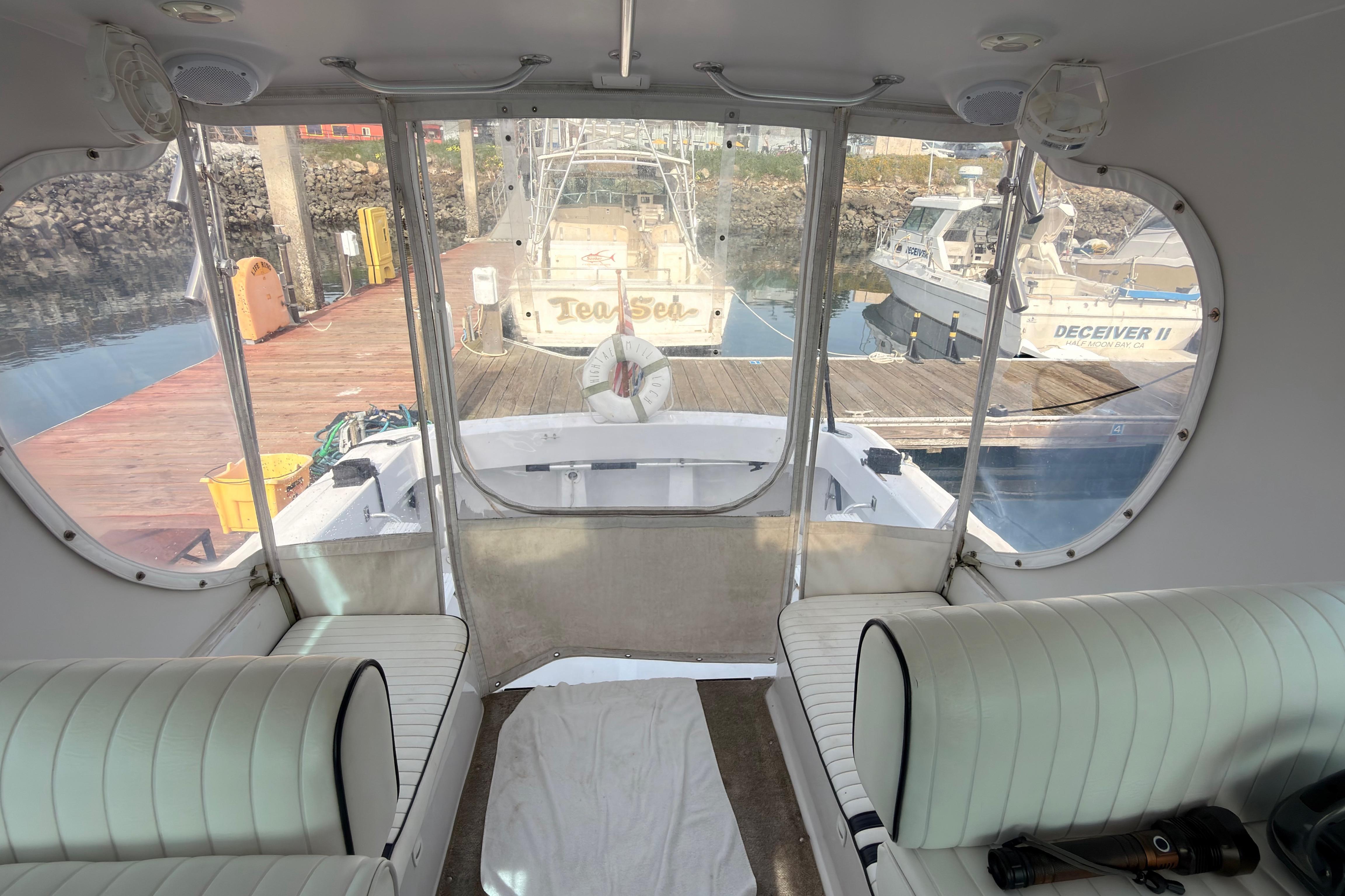 1999 Mainship Pilot 30 interior view at dock, featuring white seating and clear windows.