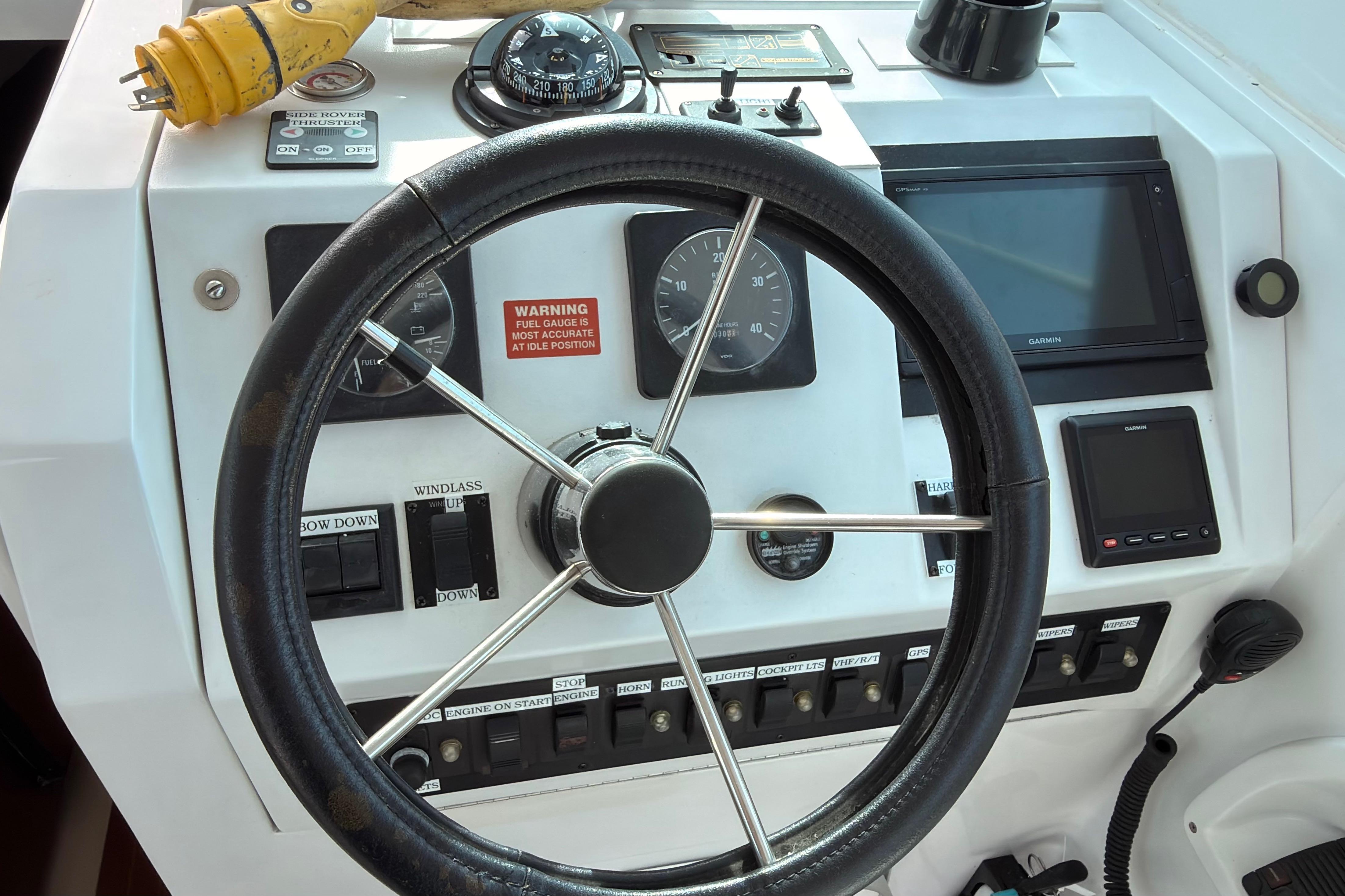 1999 Mainship Pilot 30 helm with steering wheel, gauges, and navigation equipment.