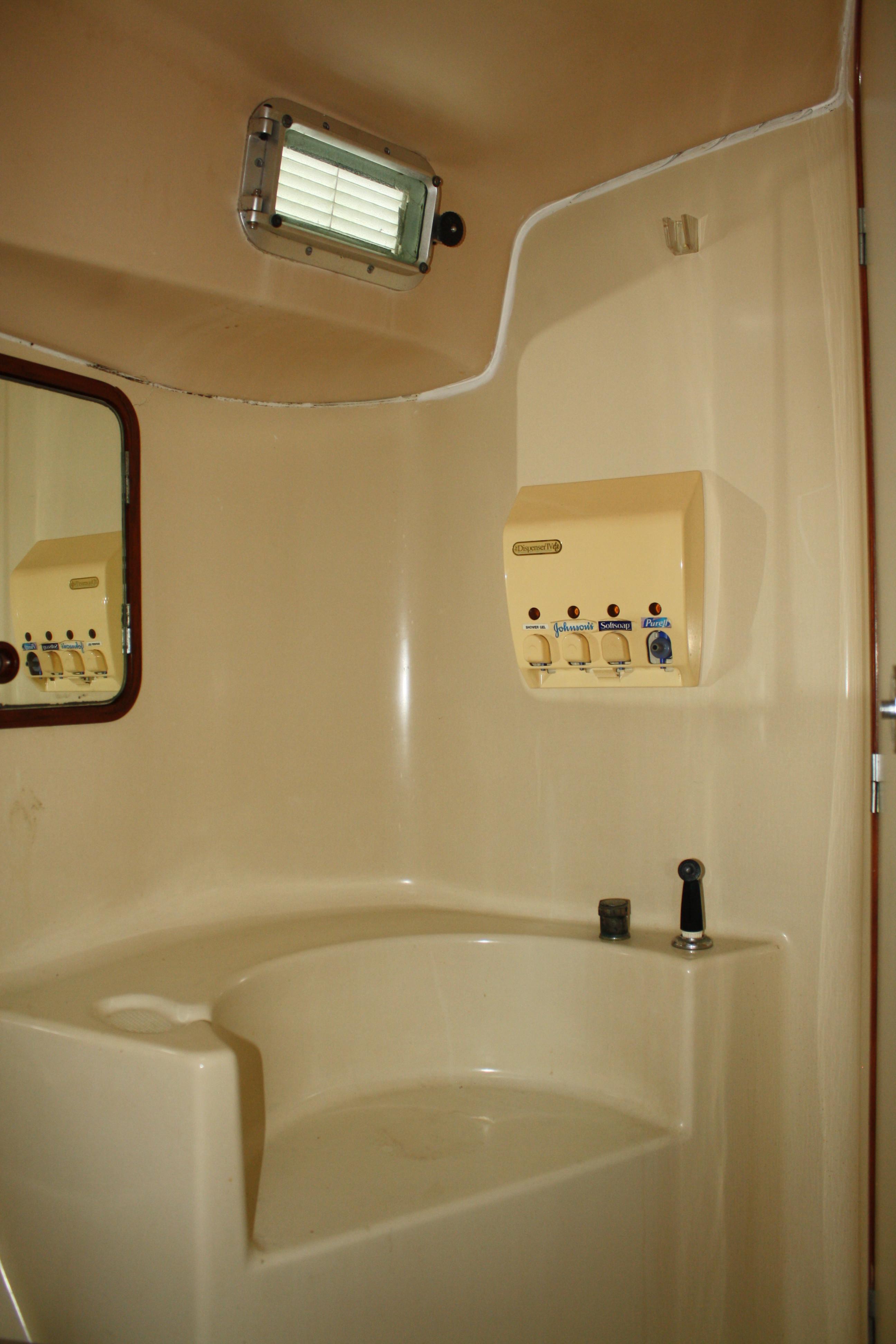 The shower portion of the single head has a large seat and is well away from the sink, head, and storage area. The gelcoat is white not cream.