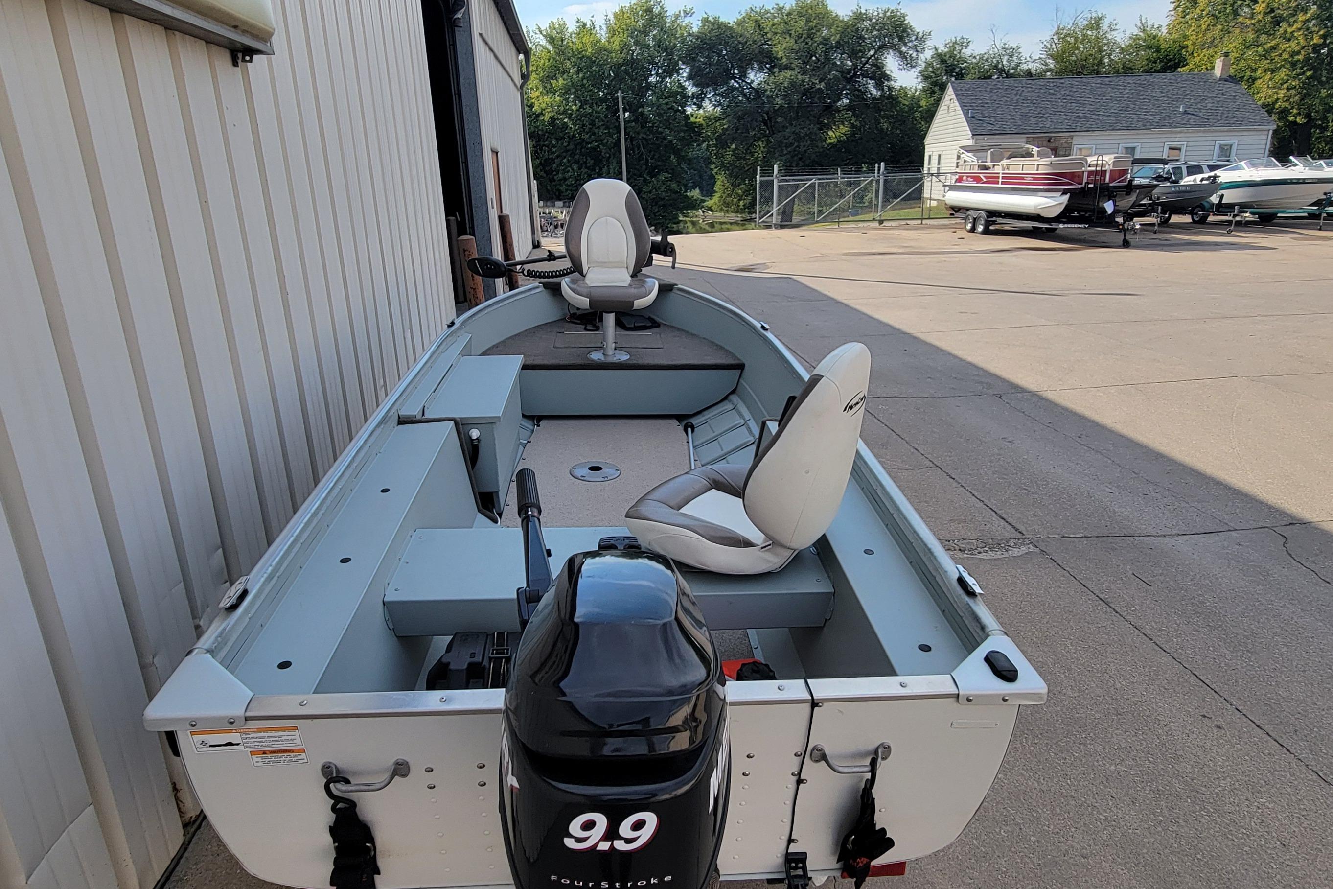 2014 MirroCraft 1400 boat with outboard motor, parked outdoors near other boats.