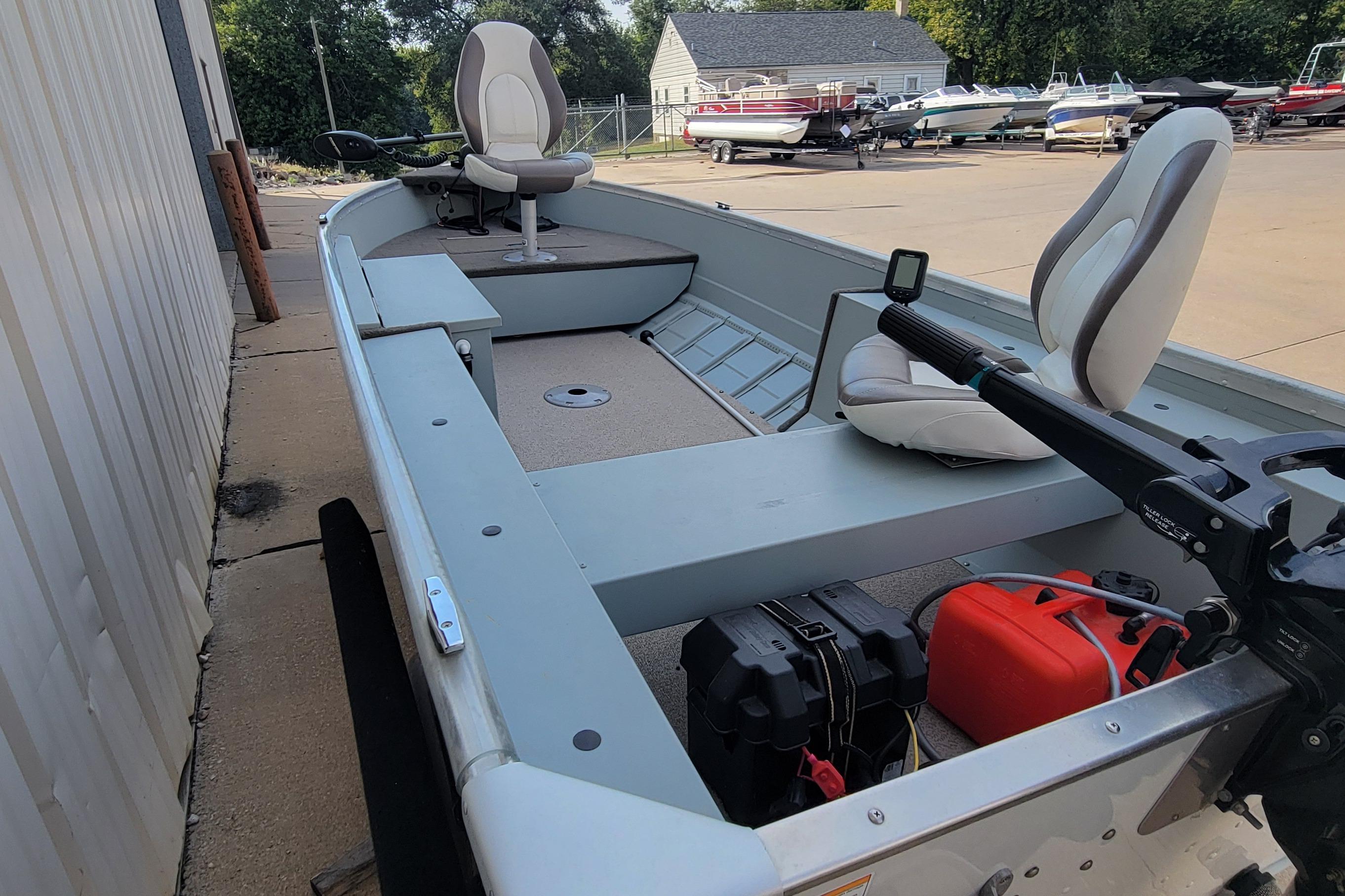 2014 MirroCraft 1400 boat with seating and motor, parked near other boats.