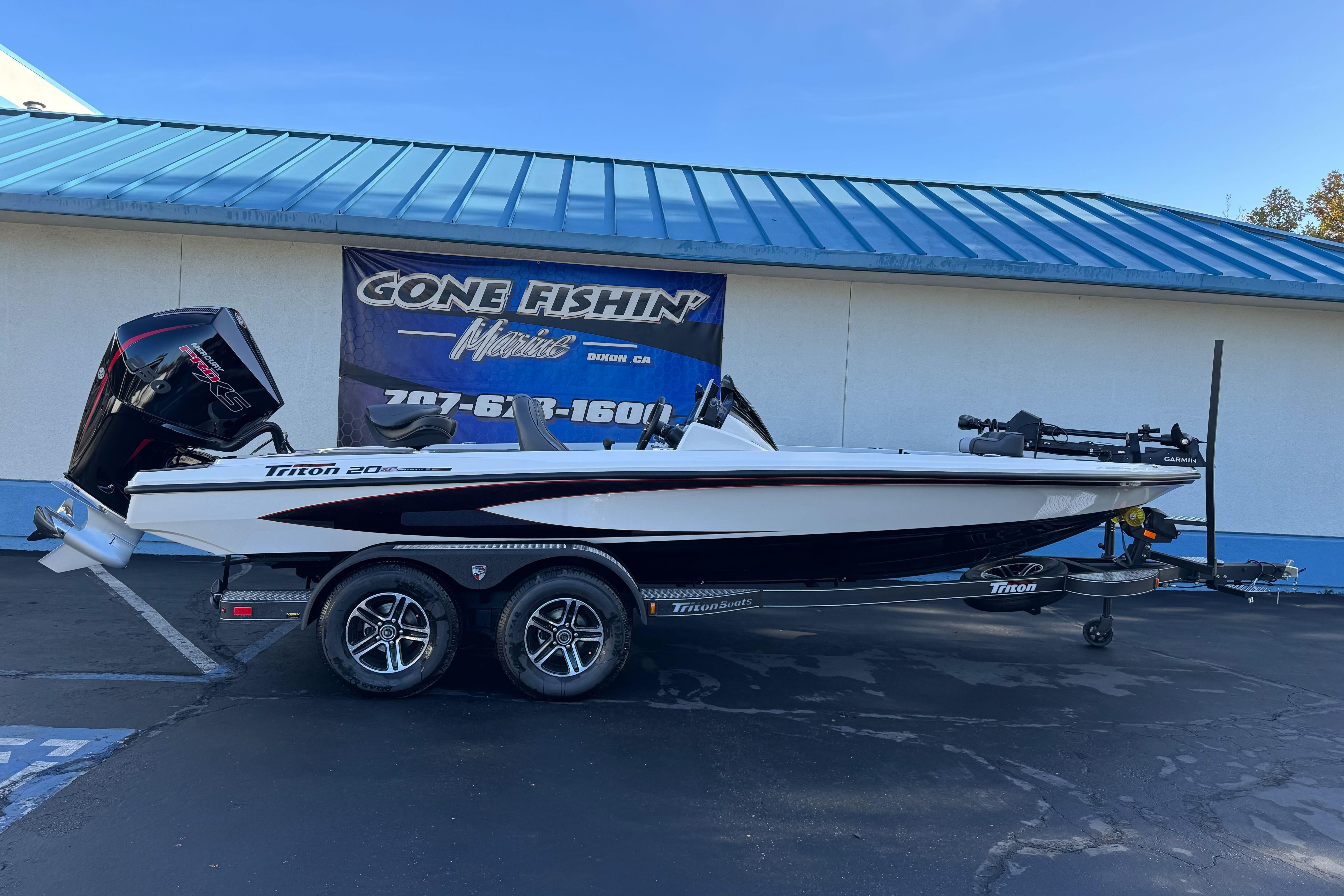 2026 Triton 20XP Patriot boat on trailer at dealership, side view.