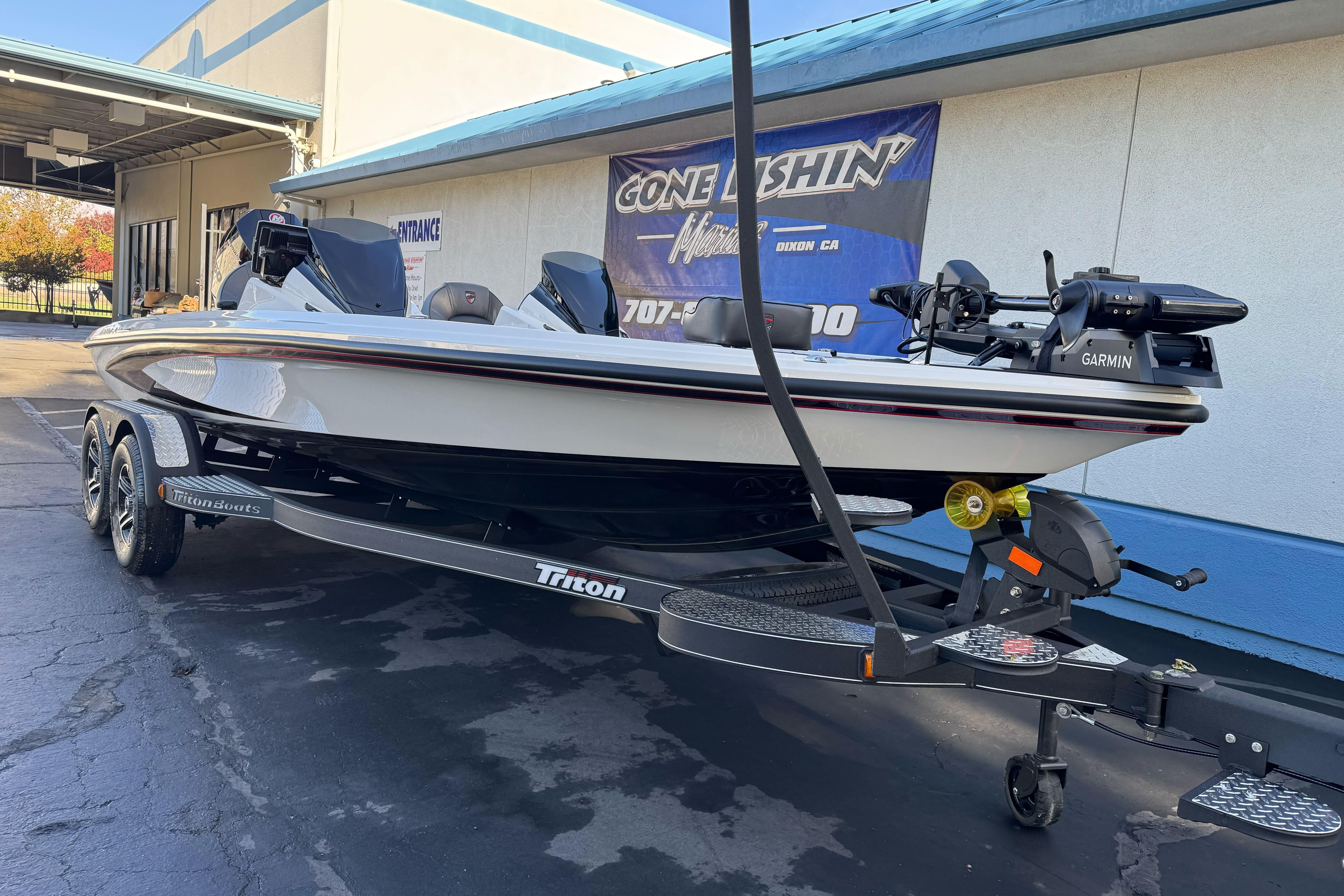 2026 Triton 20XP Patriot boat on trailer, parked outside a building.
