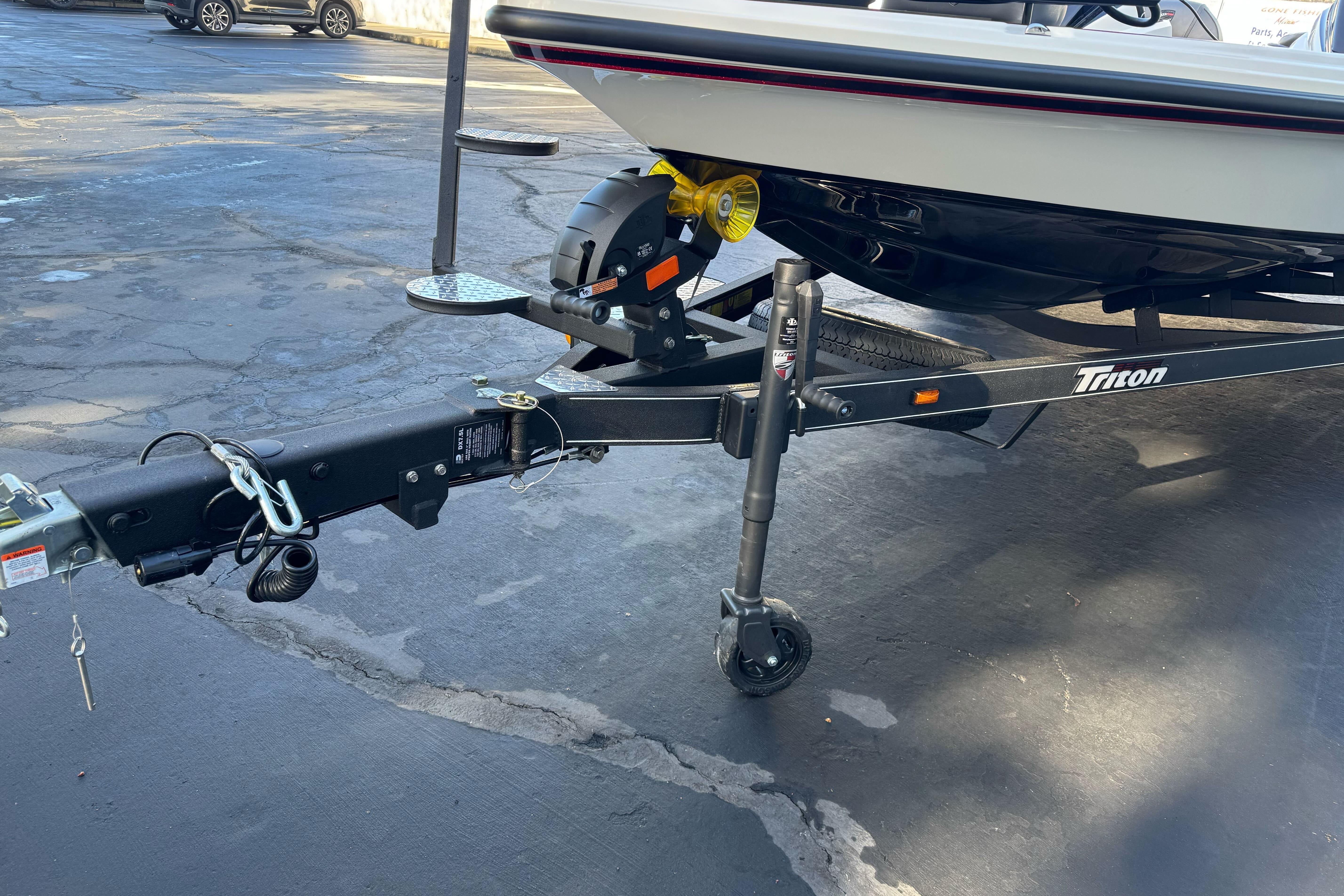 2026 Triton 20XP Patriot boat trailer hitch and wheel on pavement.