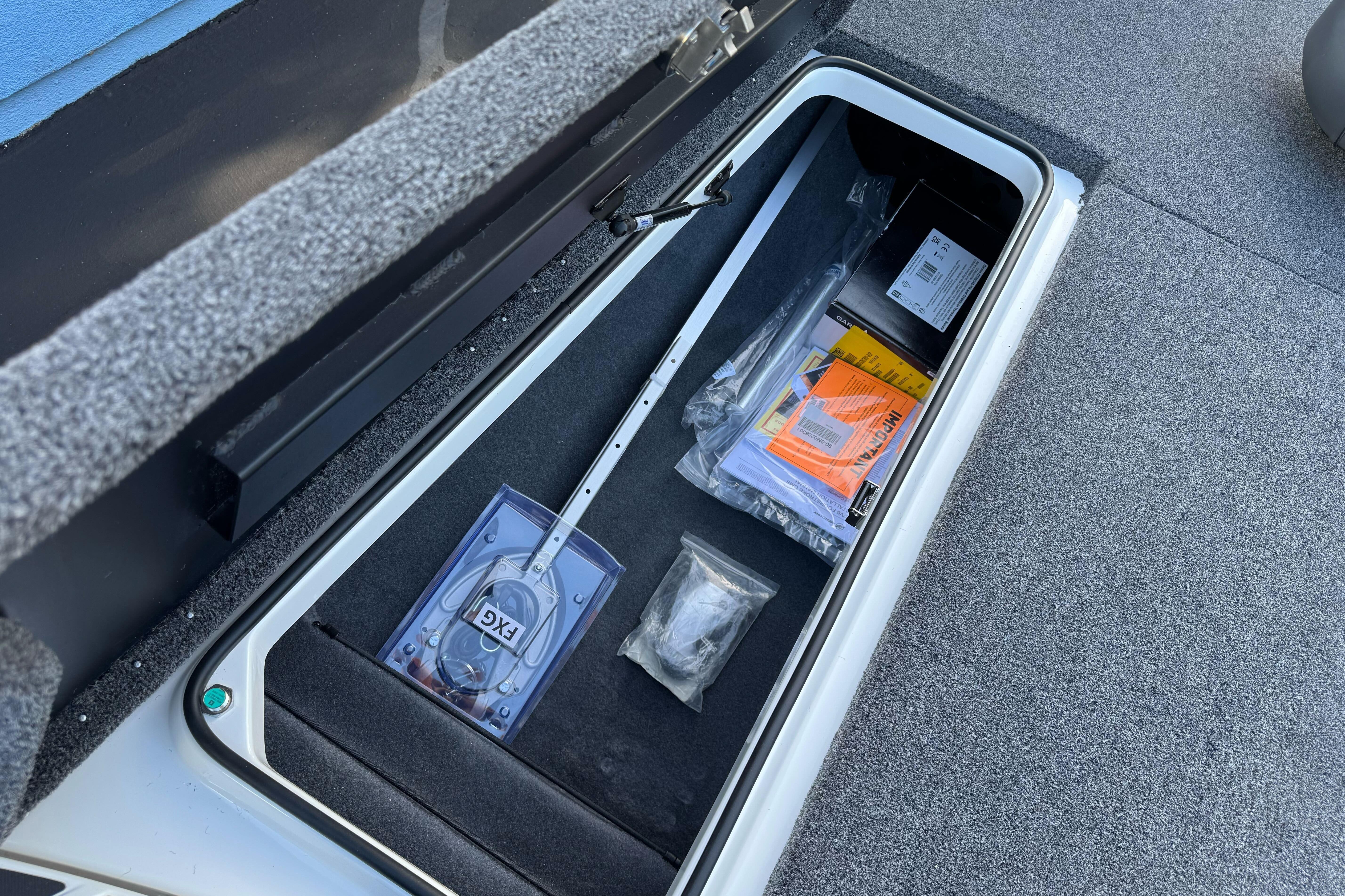 Open storage compartment in 2026 Triton 20XP Patriot boat with various items inside.