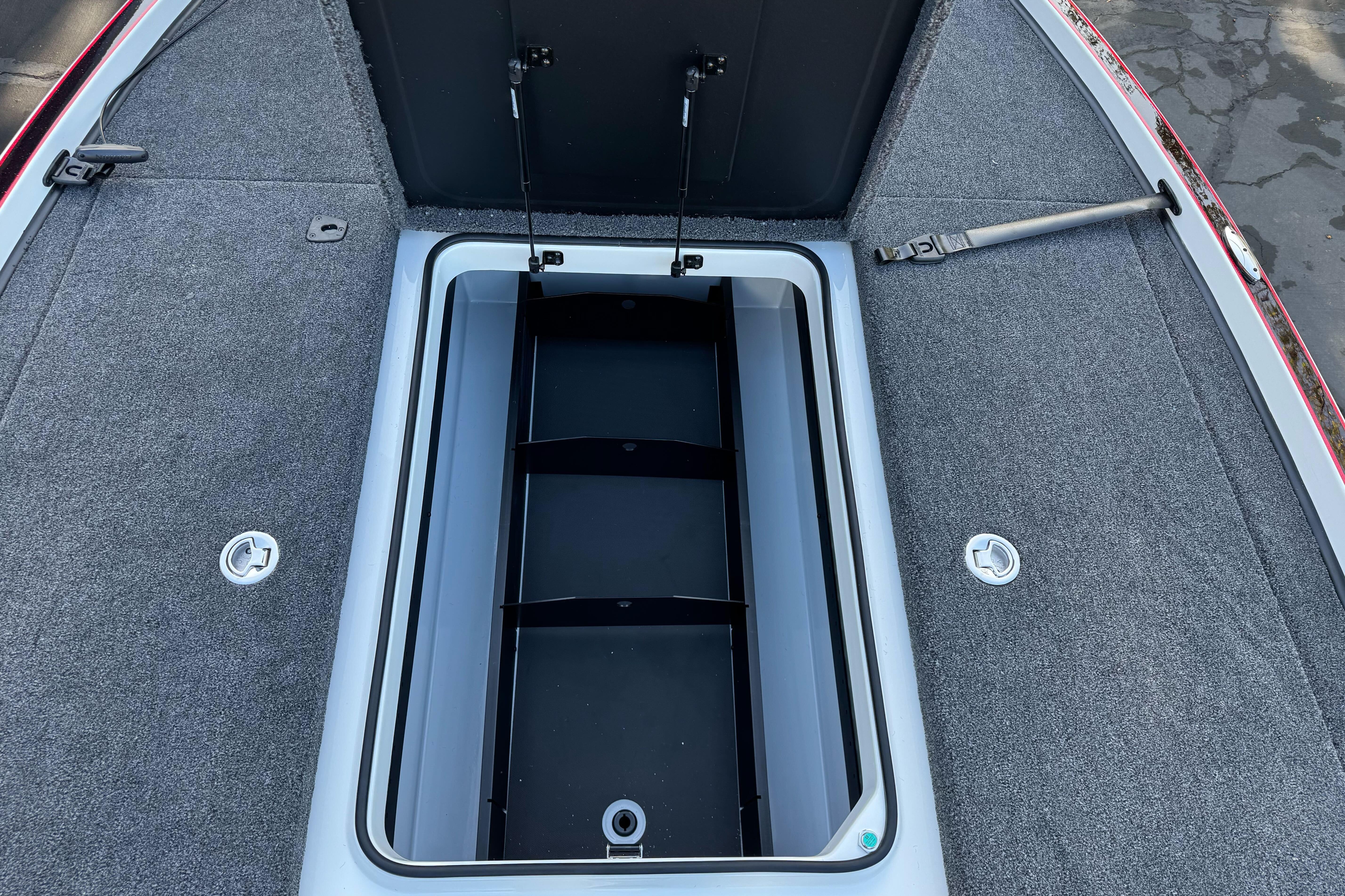 Open storage compartment on 2026 Triton 20XP Patriot boat, featuring carpeted interior.