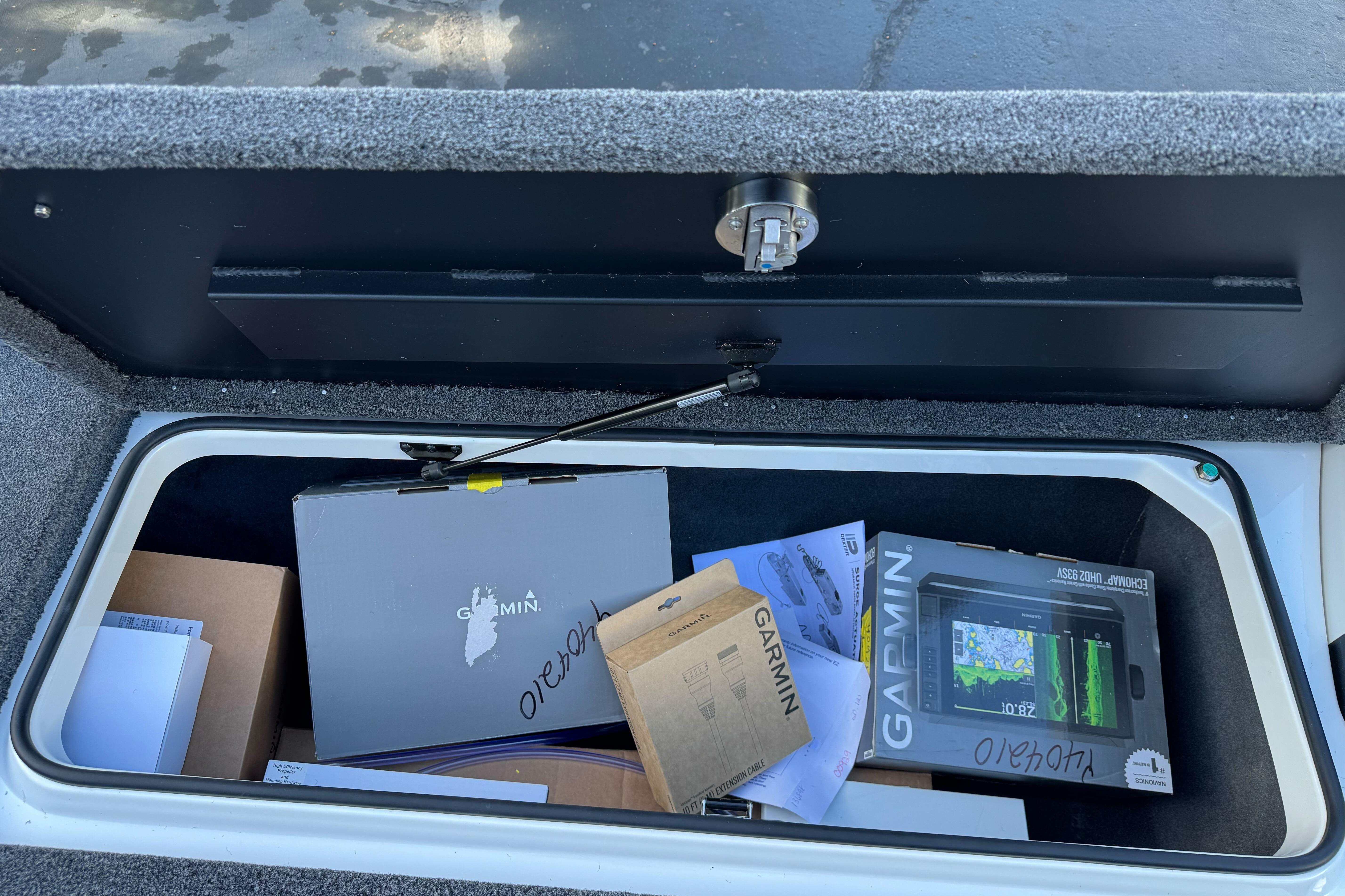 Storage compartment of 2026 Triton 20XP Patriot with Garmin electronics and documents.