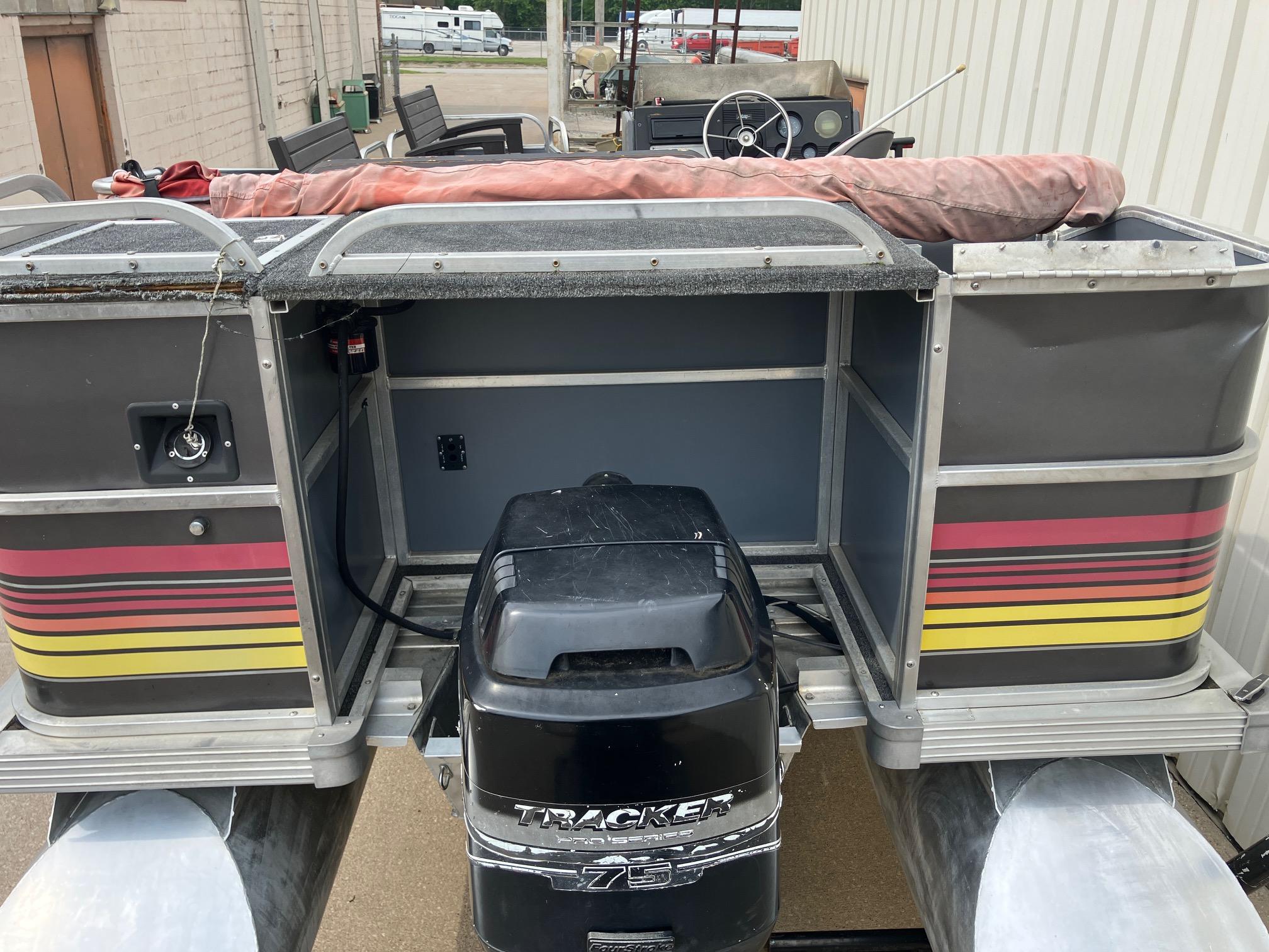 1990 Astro 24' Pontoon boat with Tracker 75 engine, docked outdoors.
