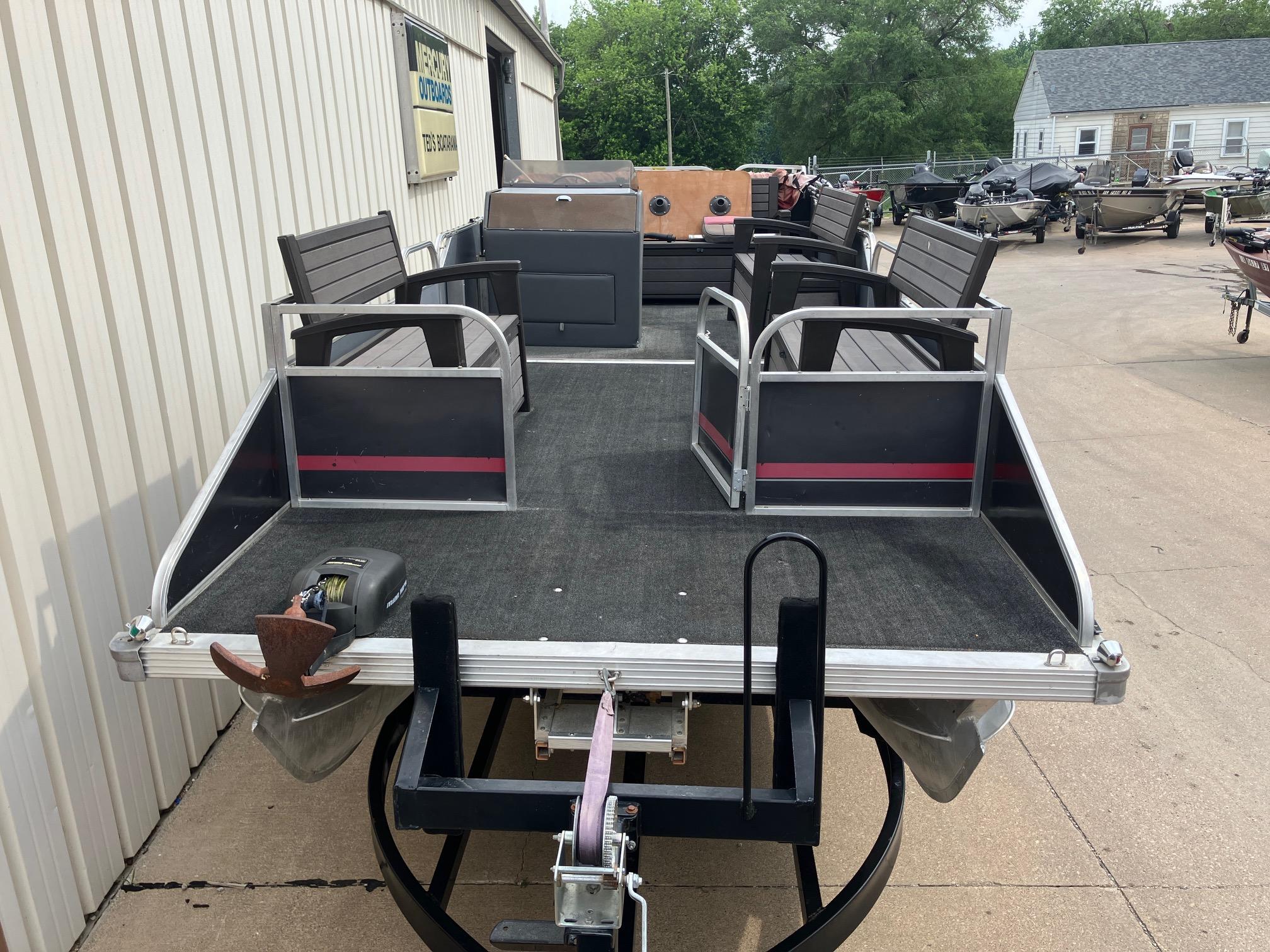1990 Astro 24' Pontoon boat with seating, docked outdoors.