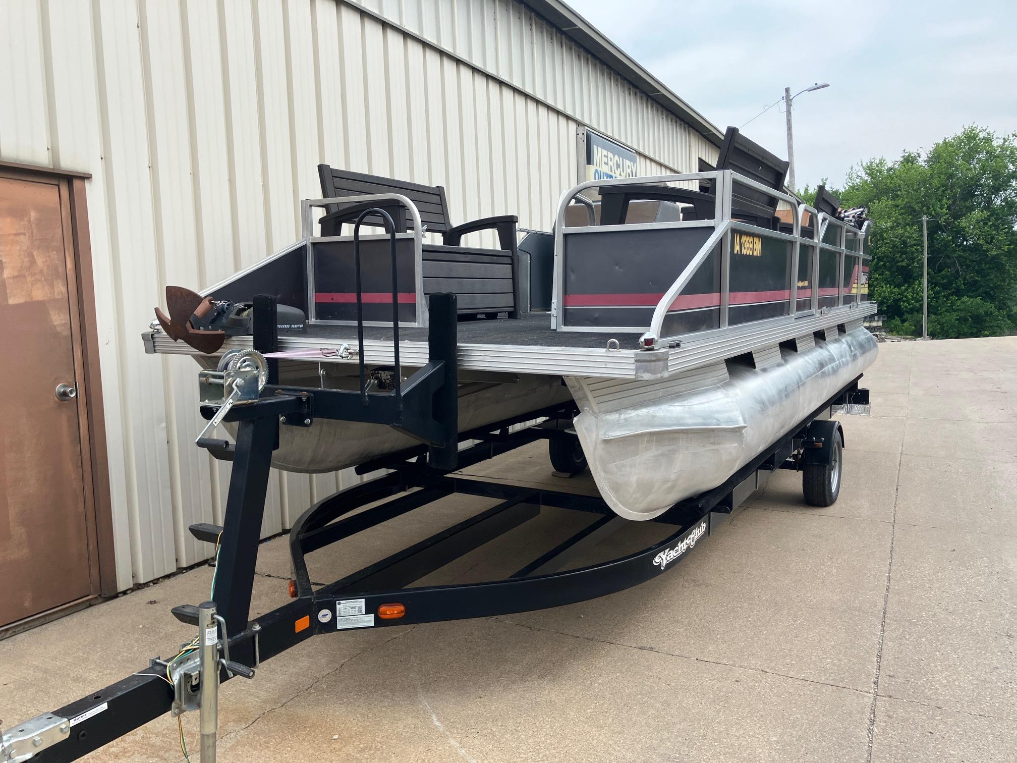 1990 Astro 24' Pontoon boat on trailer, parked beside a building.