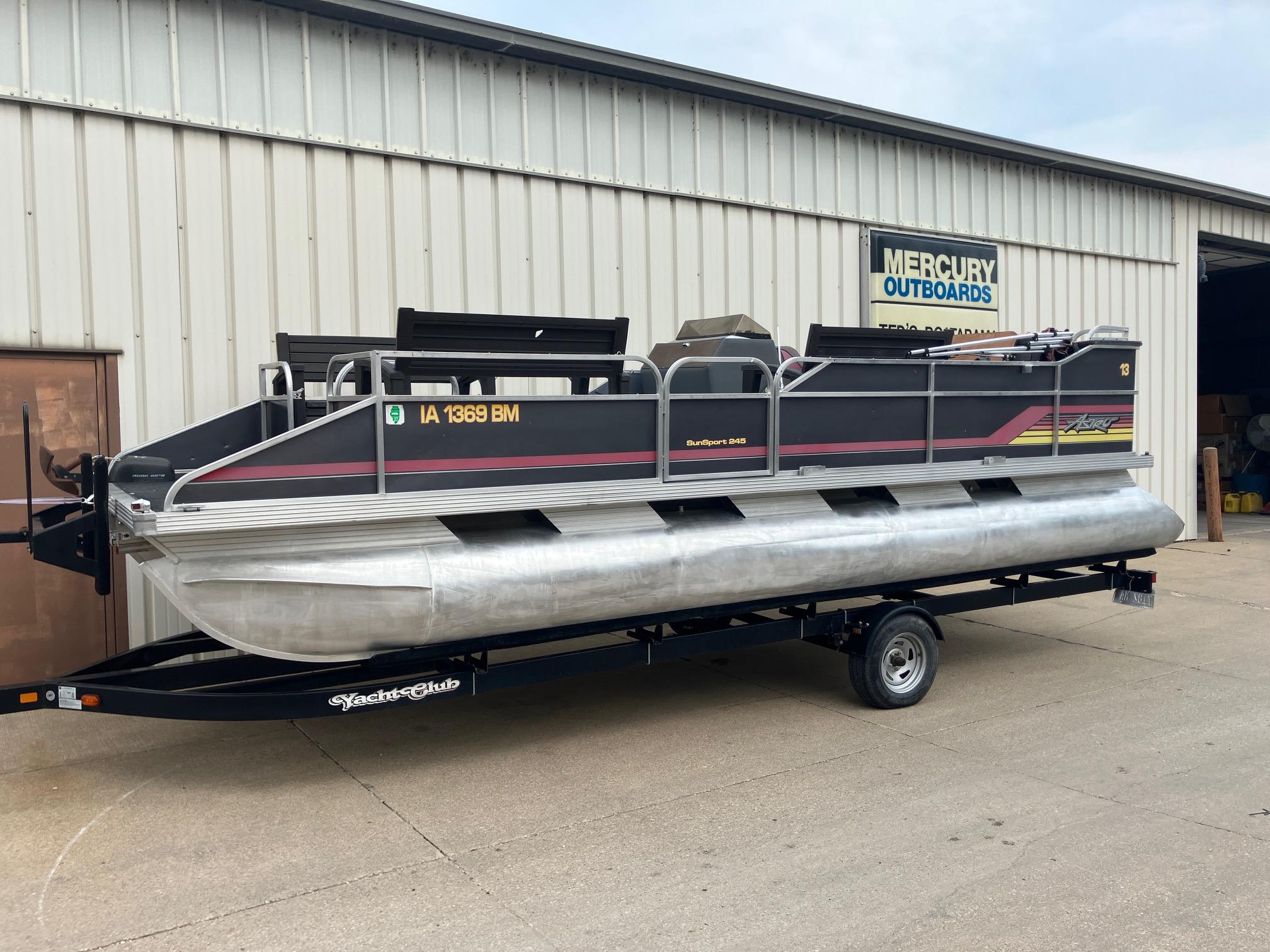 1990 Astro 24' Pontoon boat on trailer outside Mercury Outboards building.