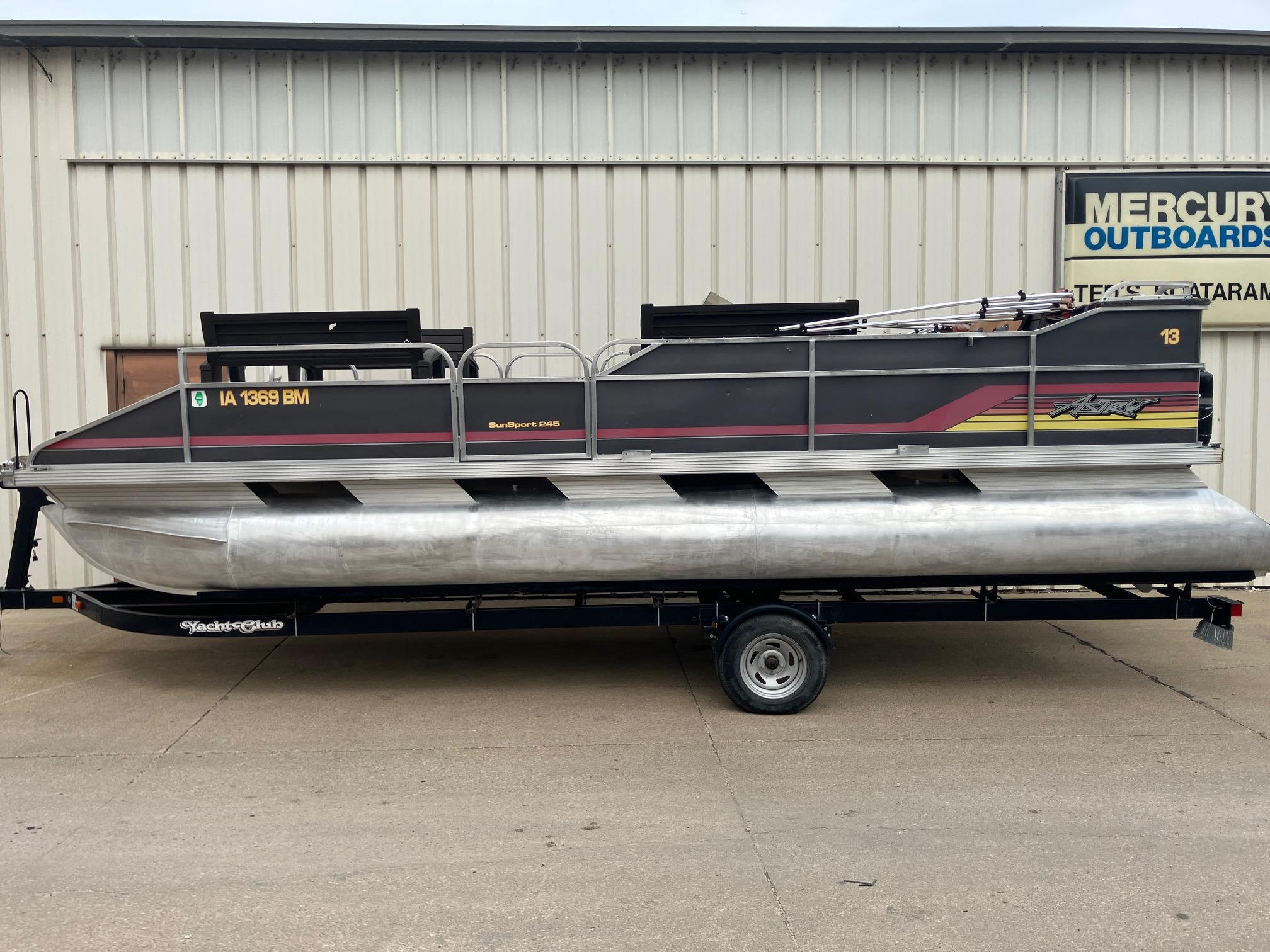 1990 Astro 24' Pontoon boat on trailer, parked outside a metal building.