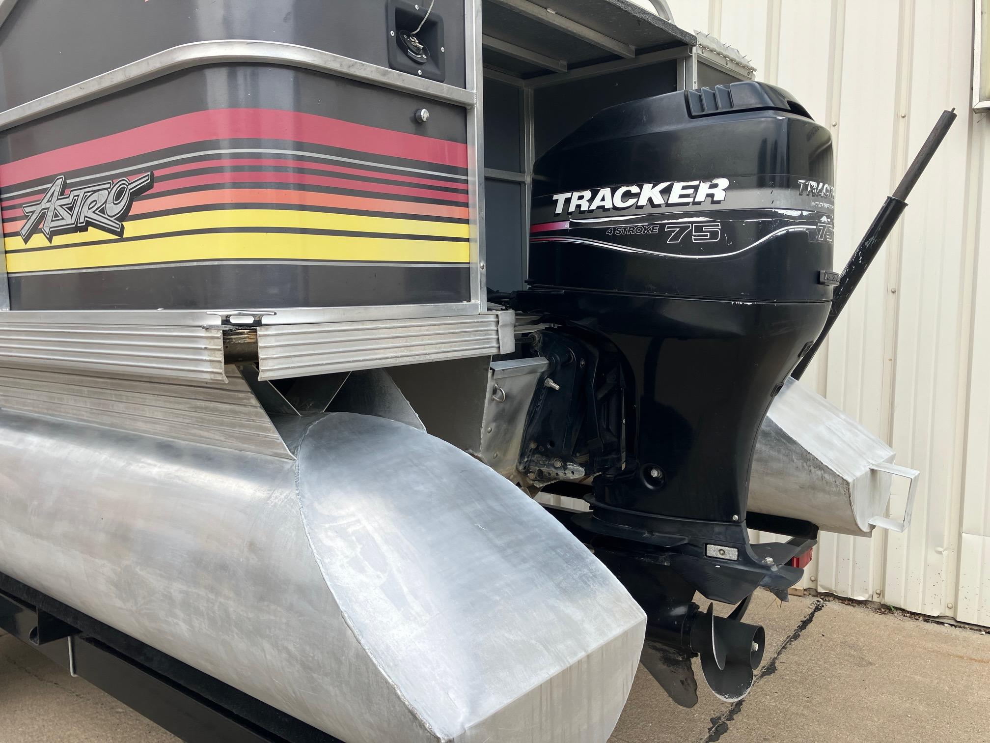 1990 Astro 24' Pontoon with Tracker 75 outboard motor, docked near a building.