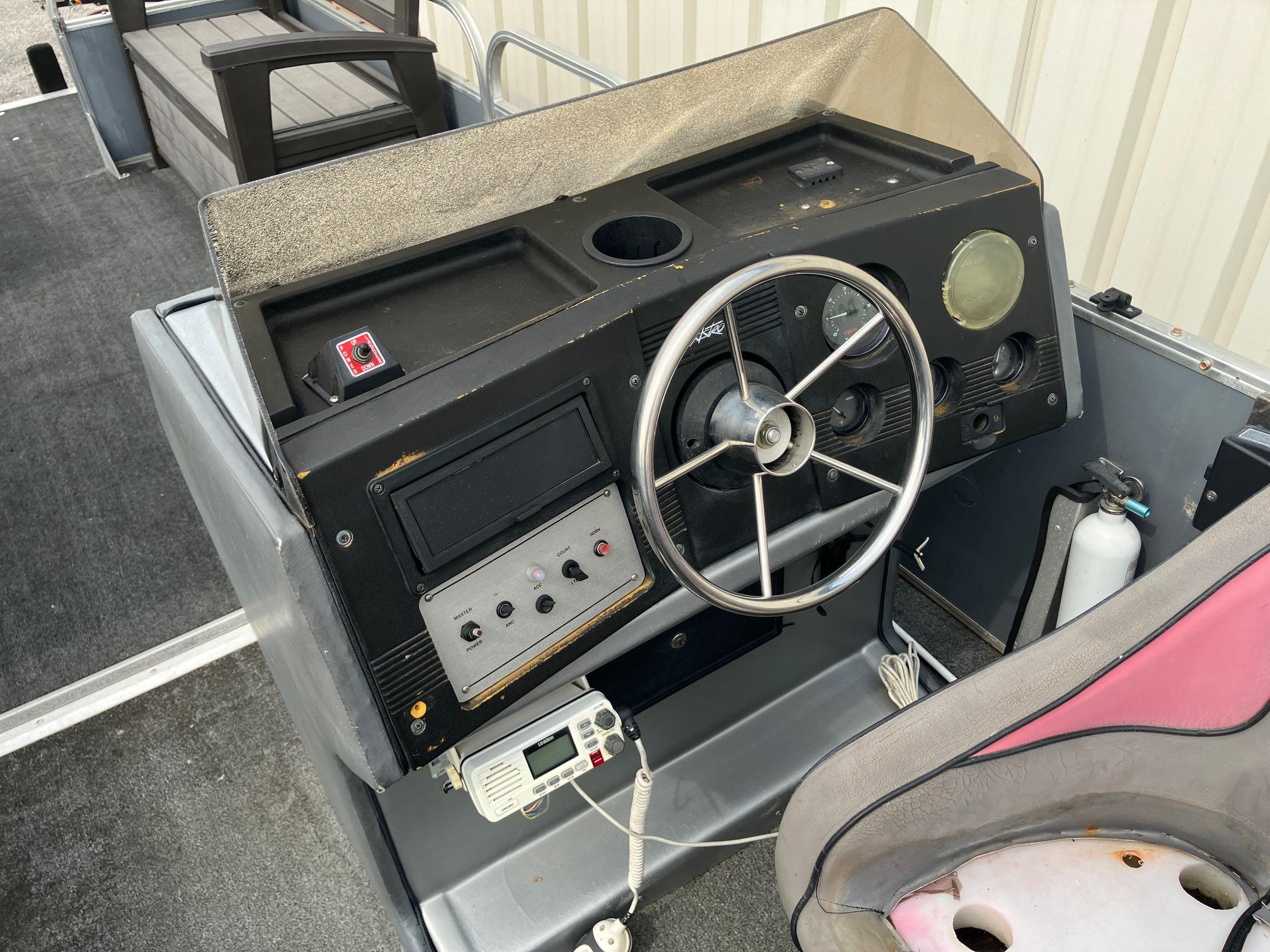 1990 Astro 24' Pontoon boat dashboard with steering wheel and control panel.