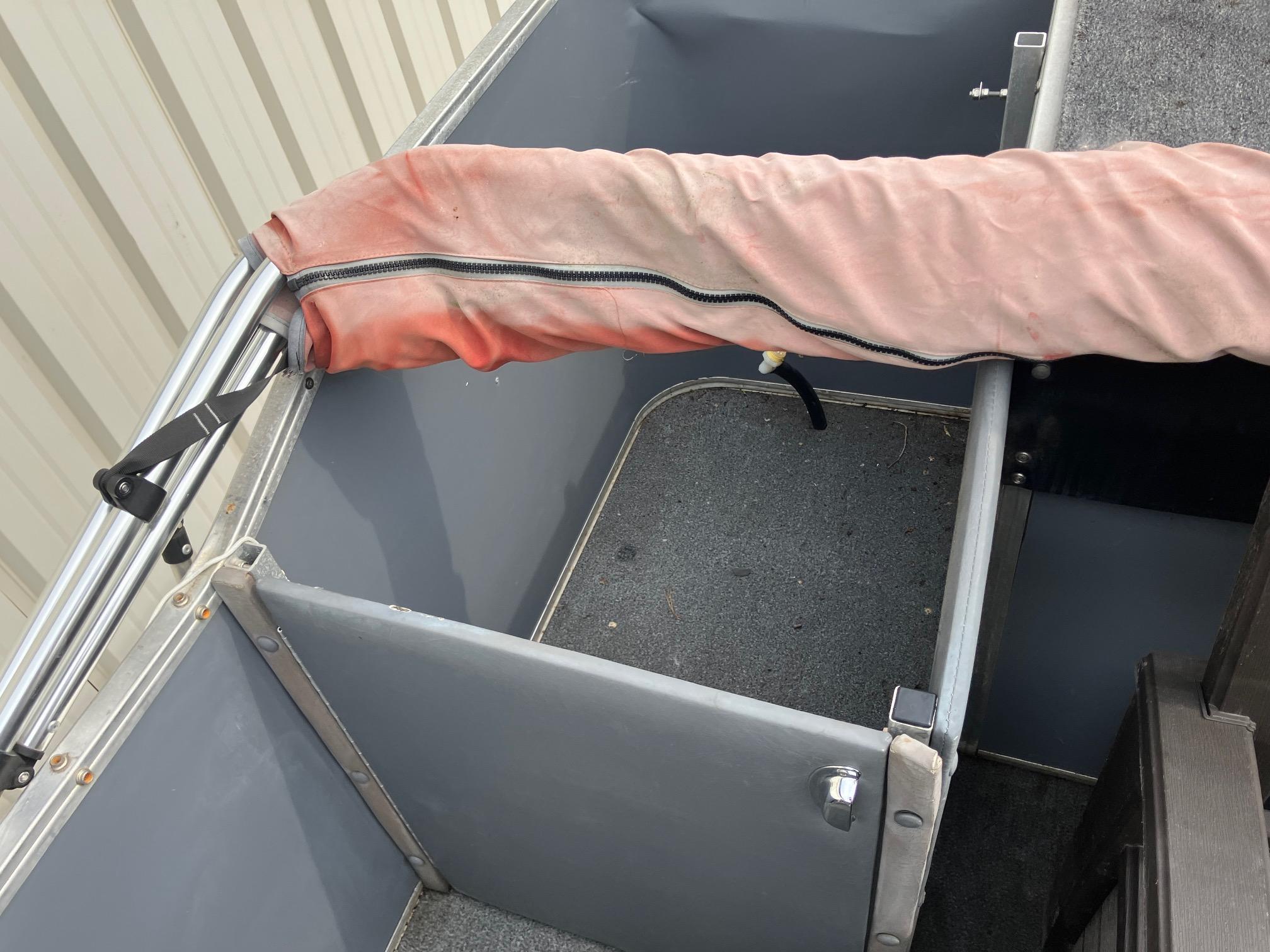 1990 Astro 24' Pontoon interior with gray flooring and a red cover.