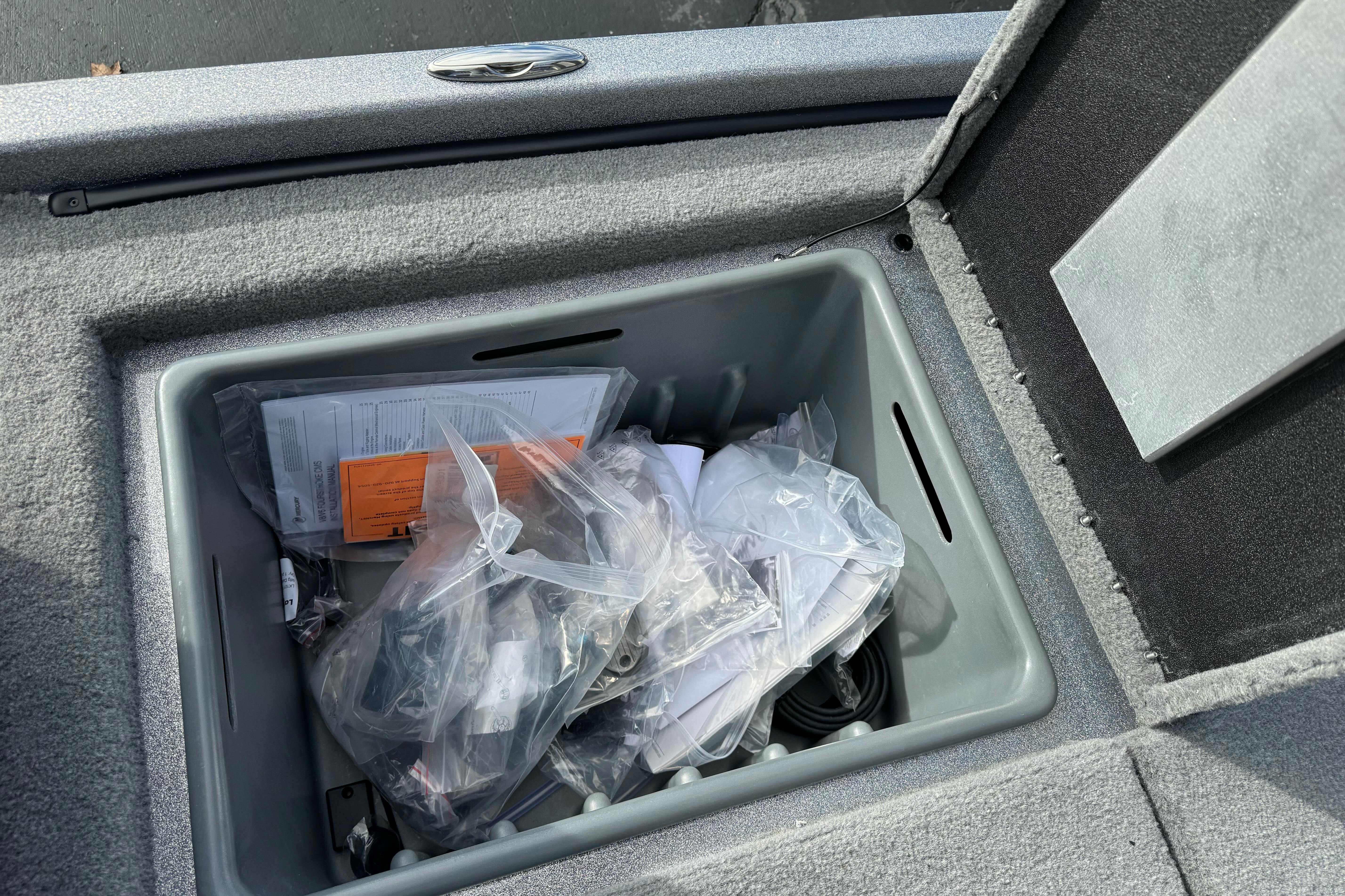 Storage compartment of 2026 Nitro Z19 XL boat with various items and documents.