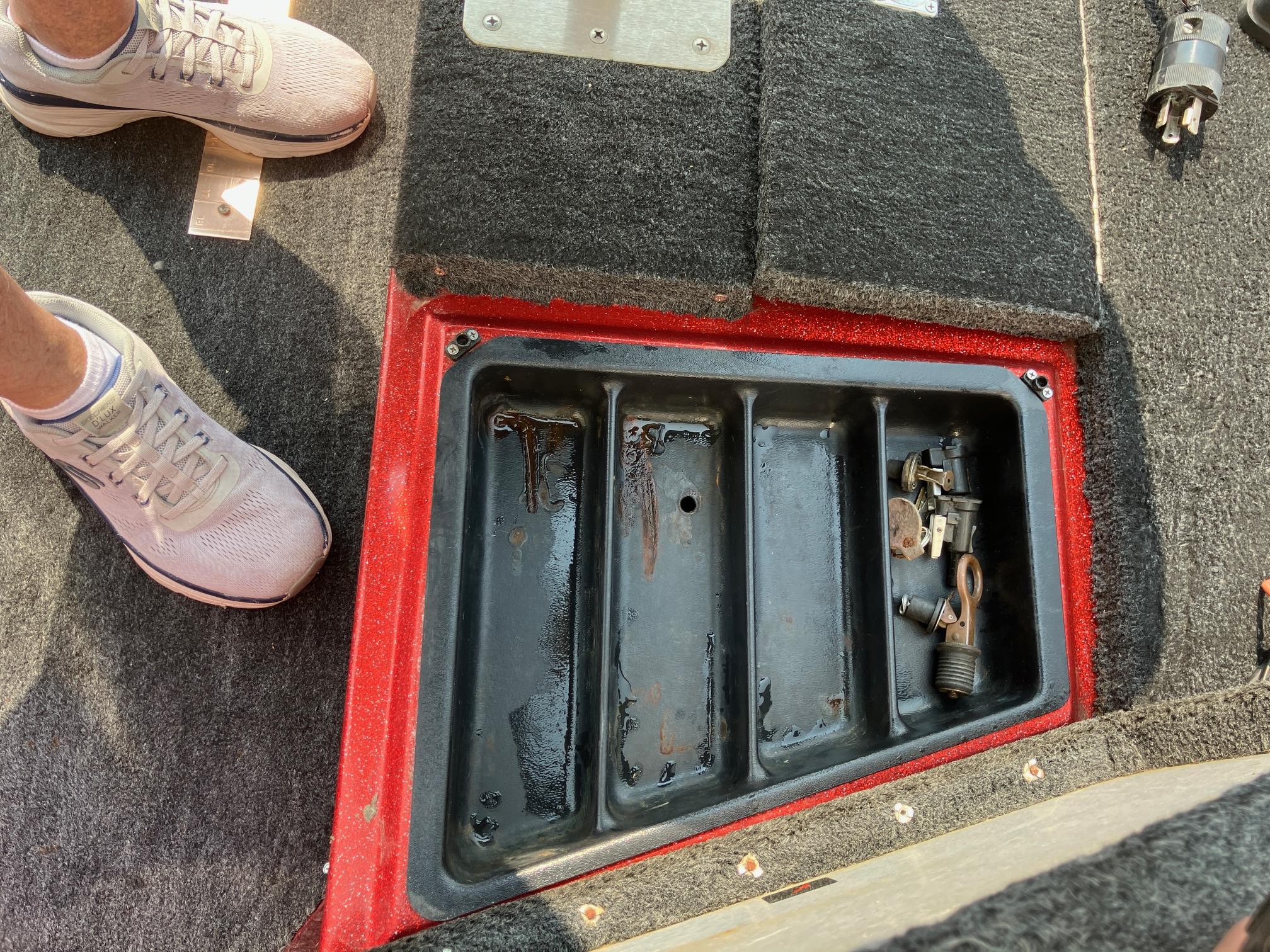 Open storage compartment on 1990 Astro 17 1/2' Bass Boat with tools inside.