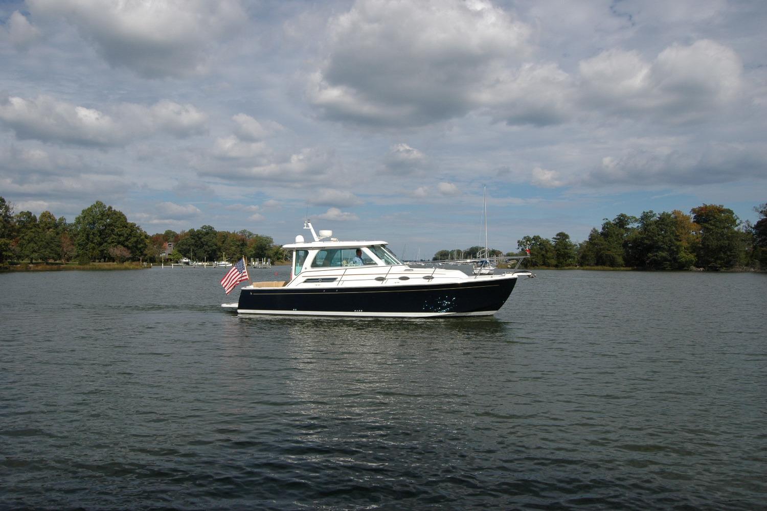 2014 Back Cove 34 boat cruising on a calm lake under a cloudy sky.