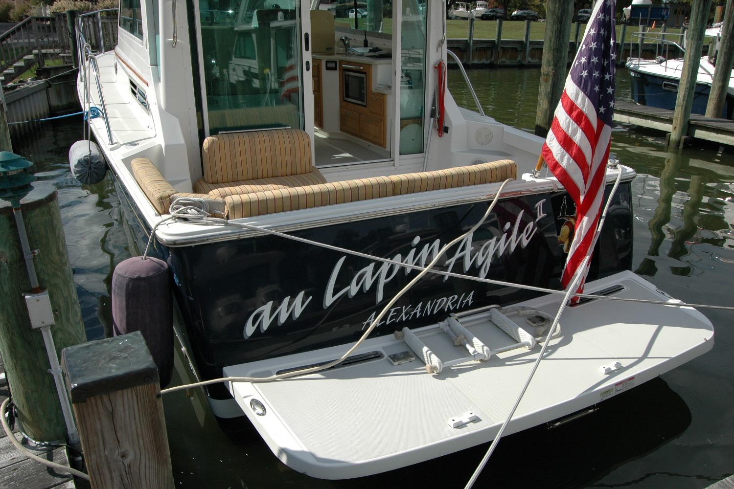 2014 Back Cove 34 boat docked, displaying American flag and cushioned seating.