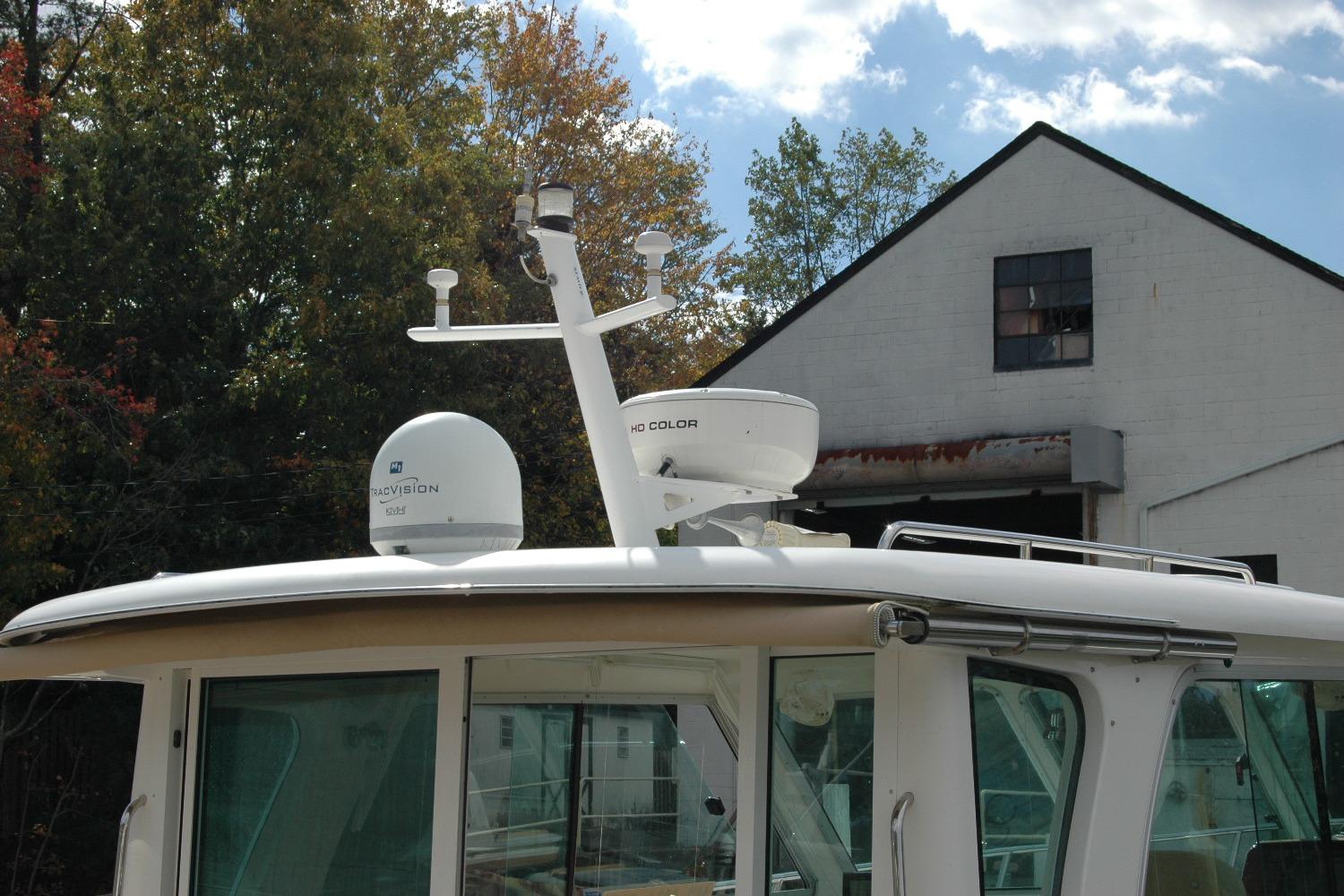 2014 Back Cove 34 boat with radar equipment, docked near a building and trees.