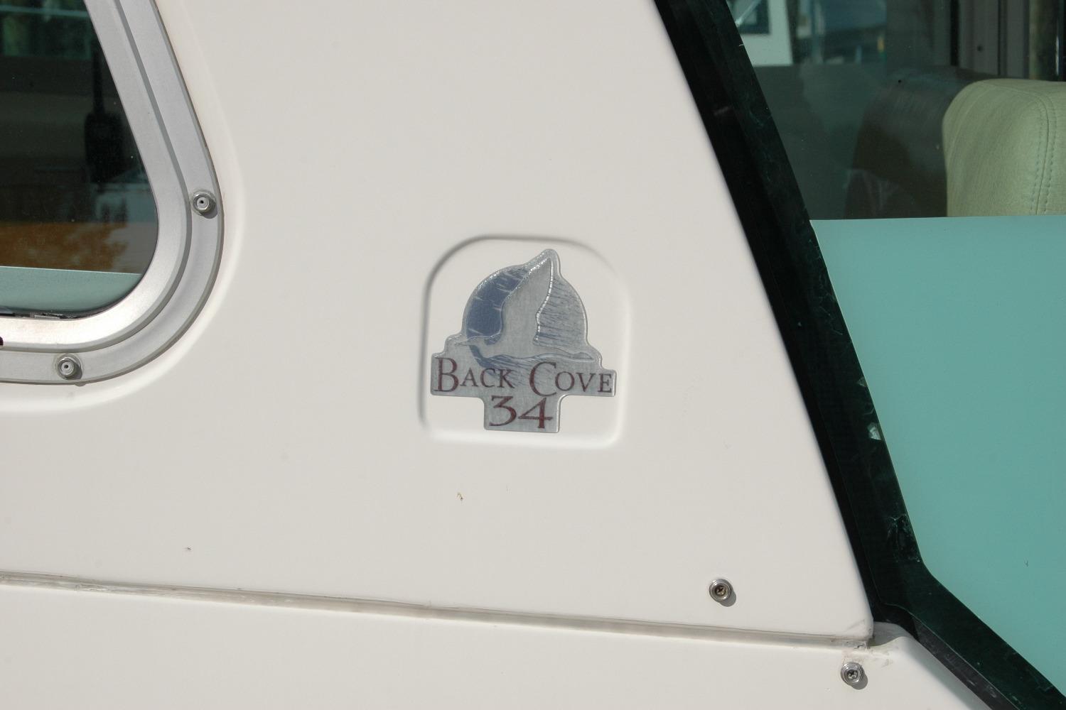 2014 Back Cove 34 boat logo on white exterior near window.