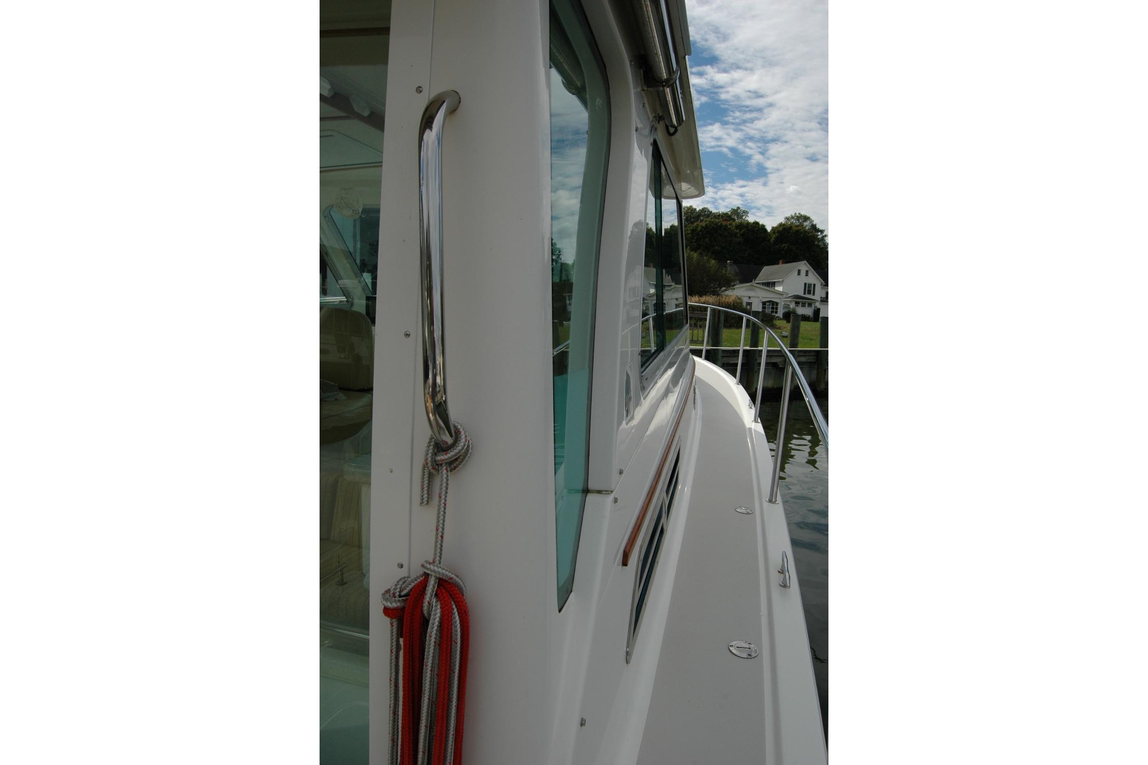 2014 Back Cove 34 boat side view with railing and docked houses in background.