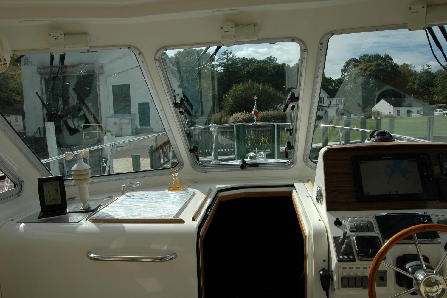2014 Back Cove 34 yacht helm with navigation equipment and scenic marina view.