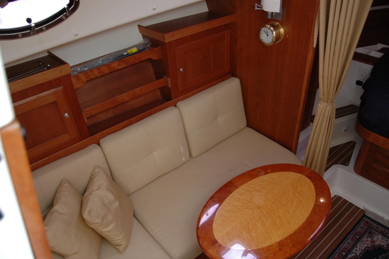 Interior of 2014 Back Cove 34 yacht with beige sofa and wooden table.