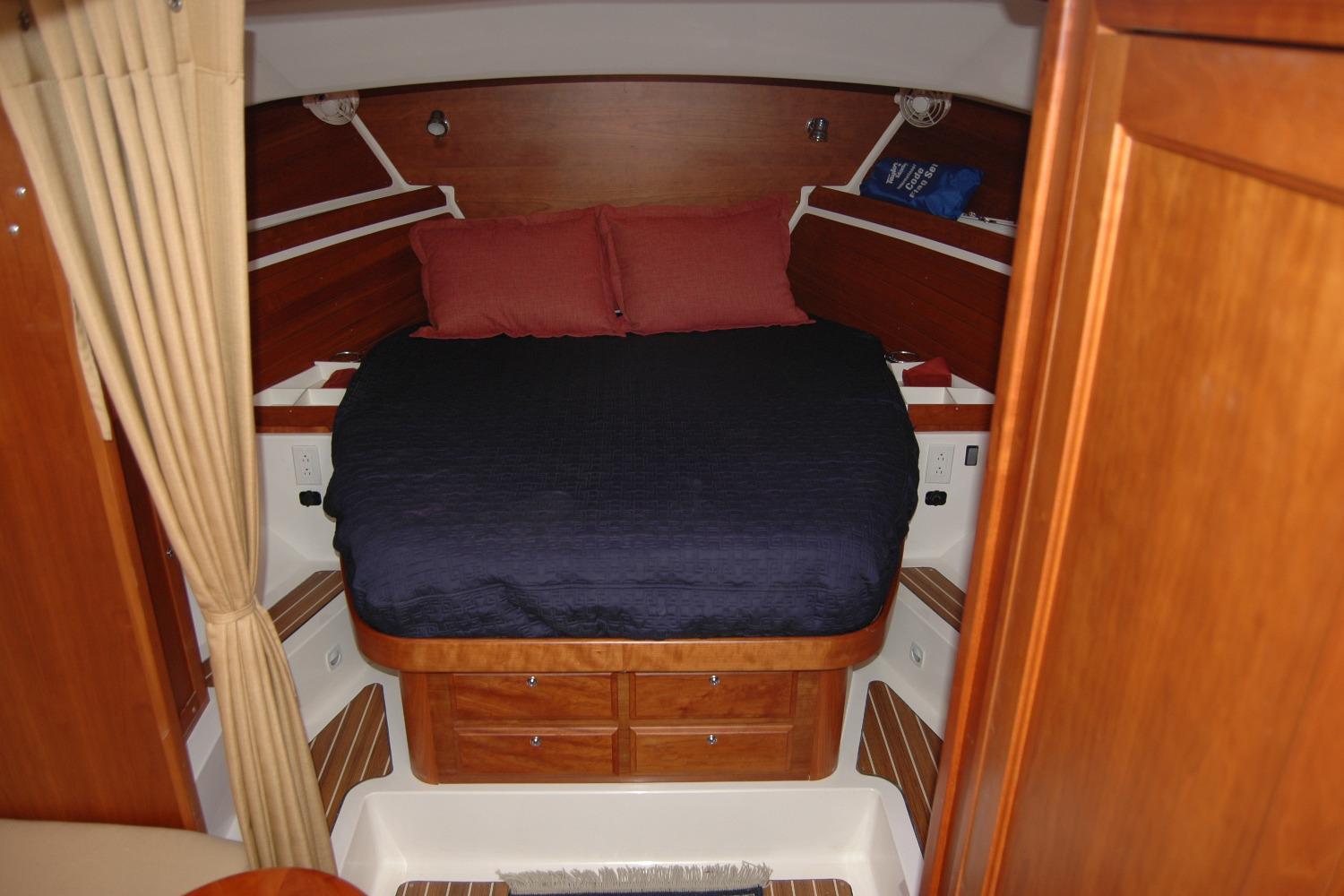 2014 Back Cove 34 cabin interior with bed, wood paneling, and storage drawers.