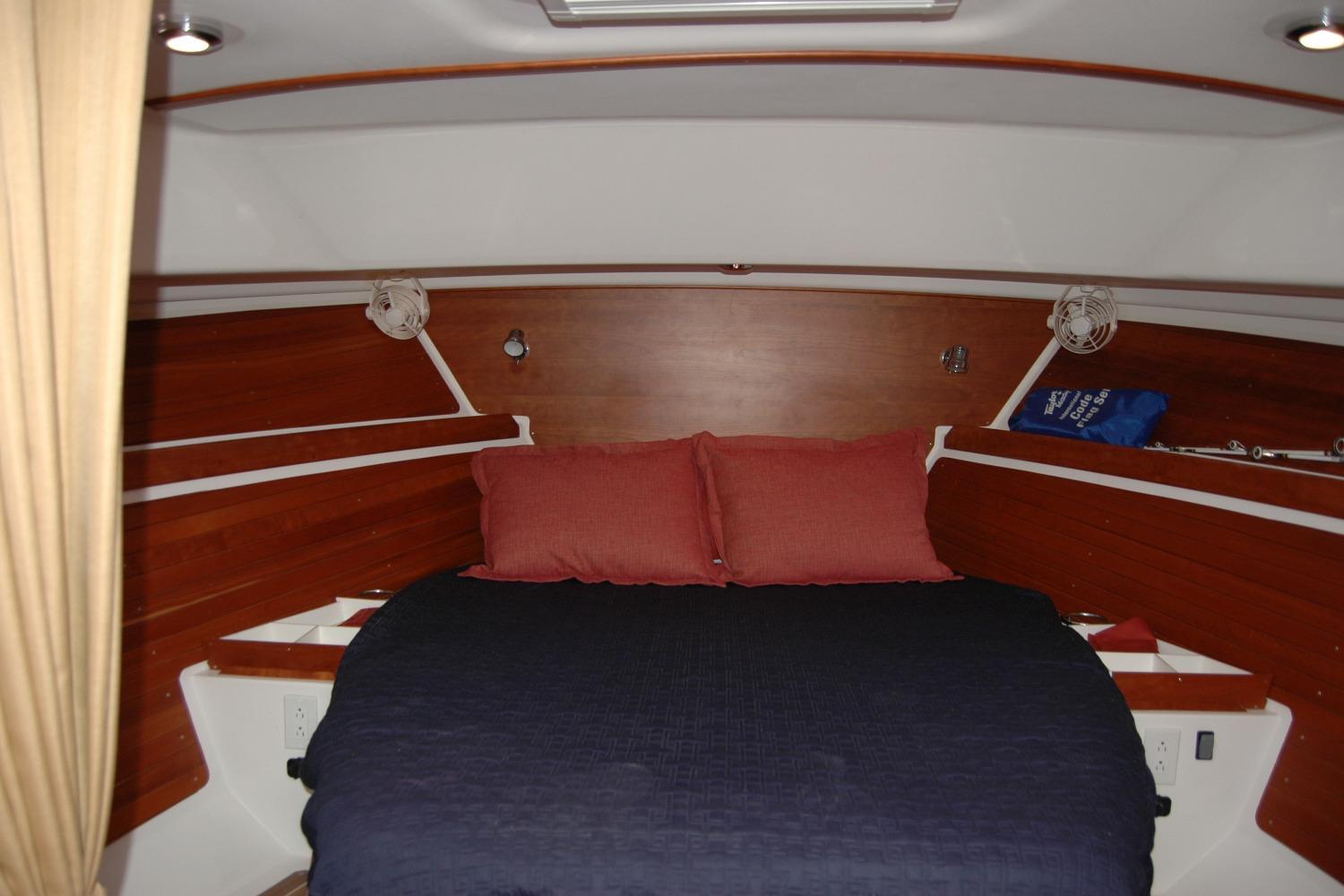 2014 Back Cove 34 cabin interior with cozy bed and wooden accents.