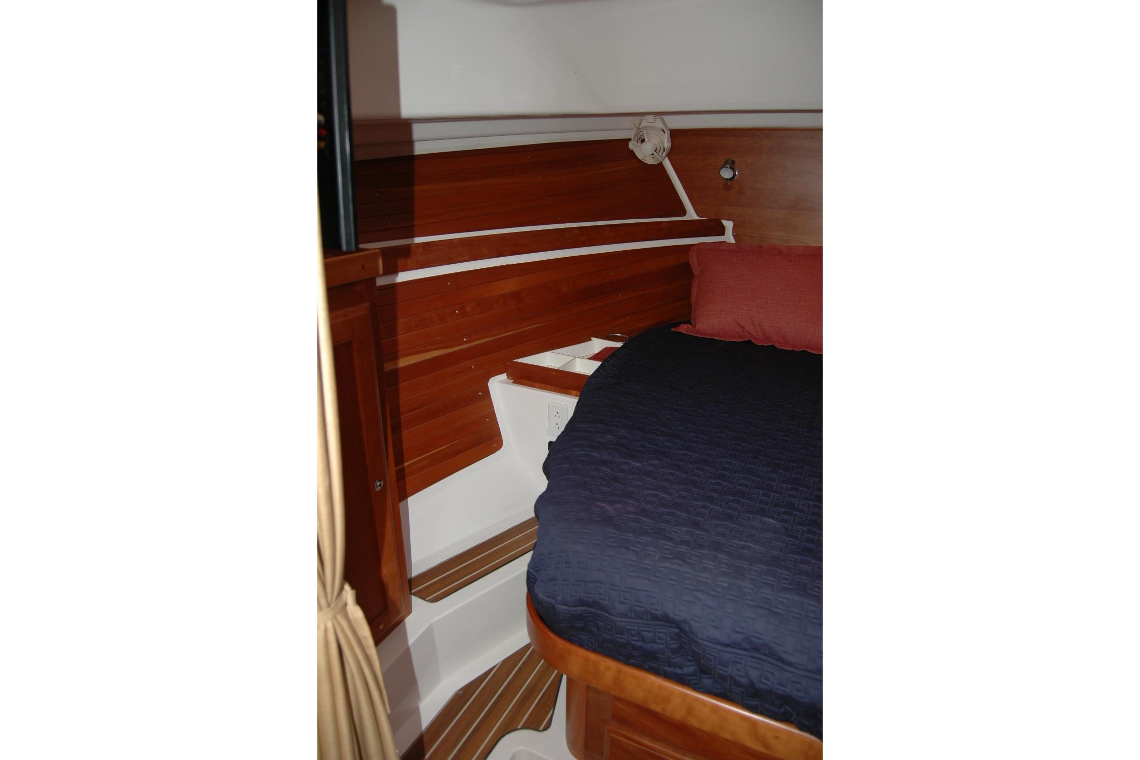 Interior cabin of 2014 Back Cove 34 boat with wooden paneling and cozy bedding.