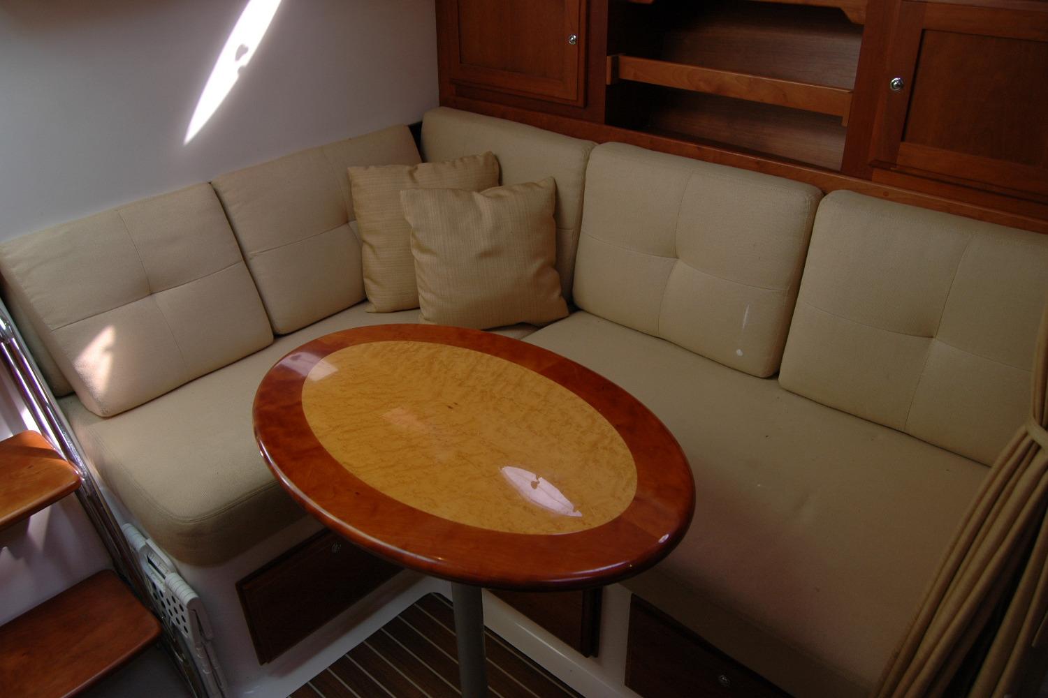 Interior of 2014 Back Cove 34 with beige seating and wooden table.