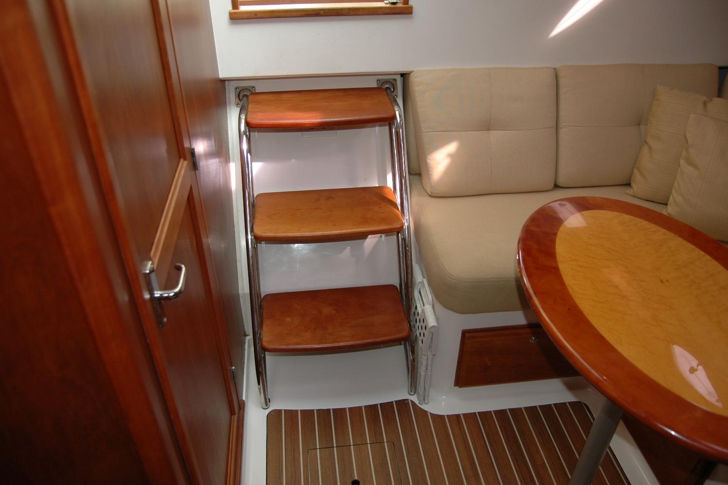 Interior of 2014 Back Cove 34 yacht with wooden steps, cushioned seating, and oval table.