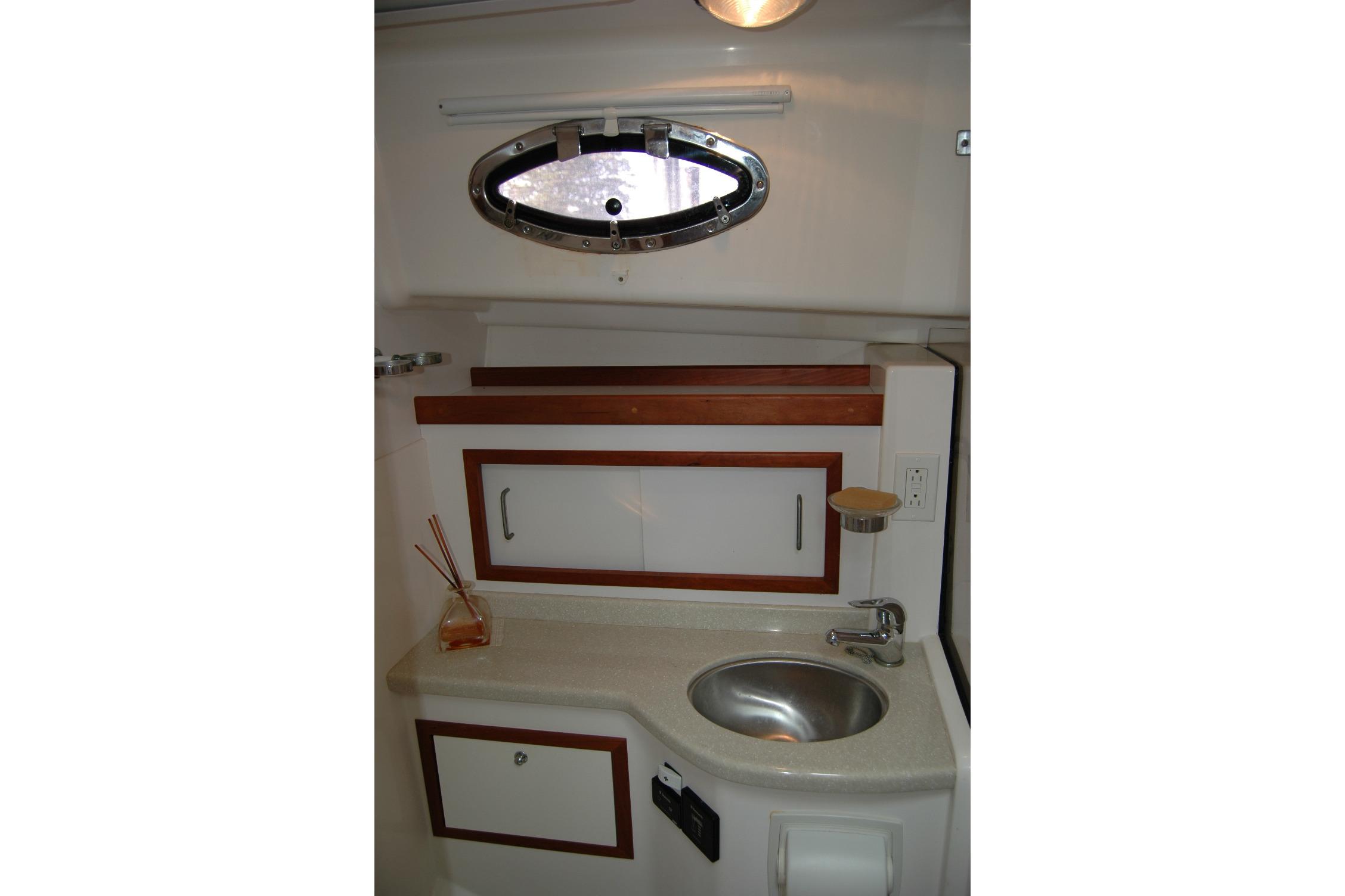 2014 Back Cove 34 yacht bathroom with sink, porthole, and wooden cabinetry.