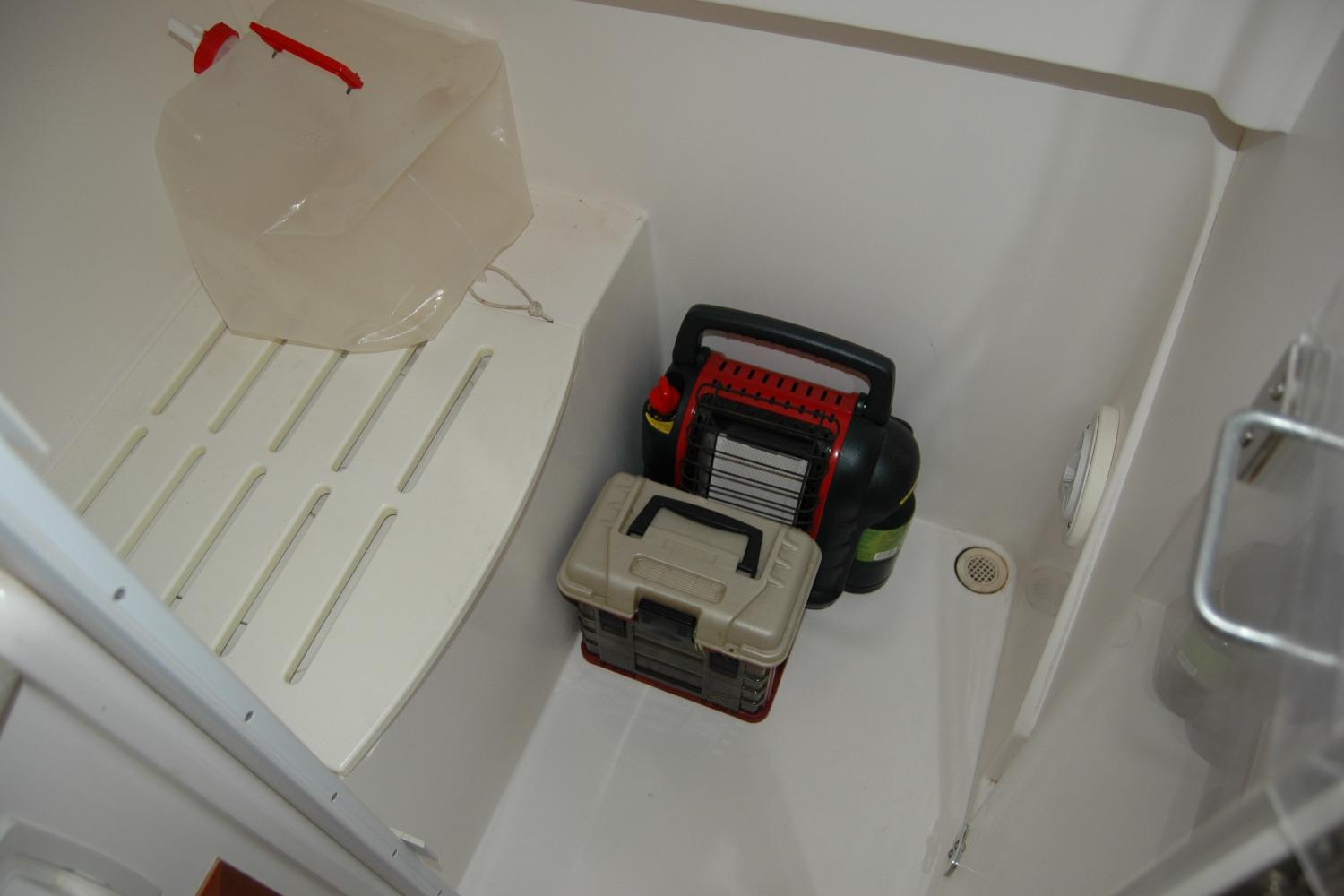 Storage compartment in 2014 Back Cove 34 boat with tools and a water container.