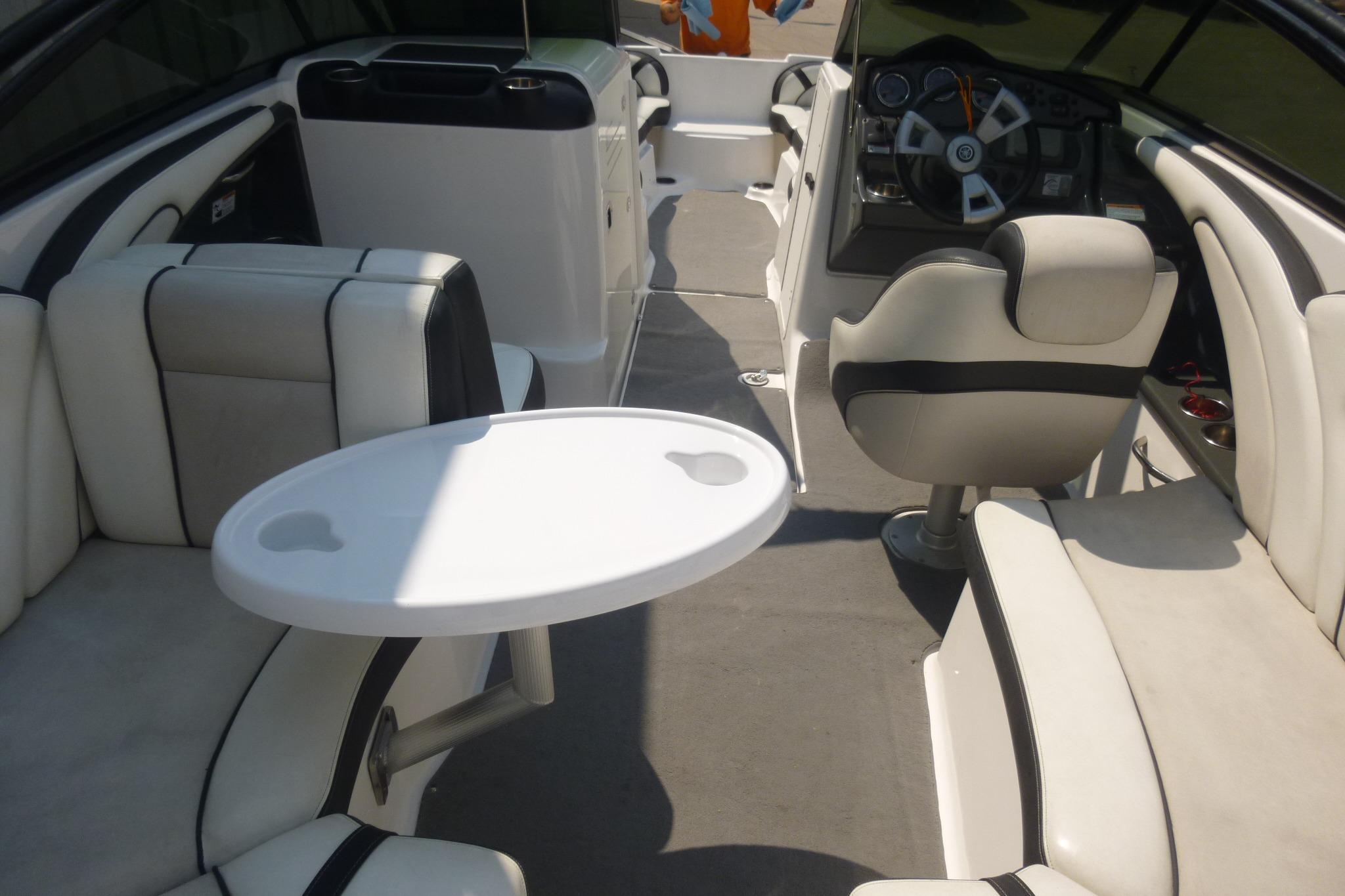 Interior of 2014 Yamaha Boats 240, featuring seating and steering area with a small table.