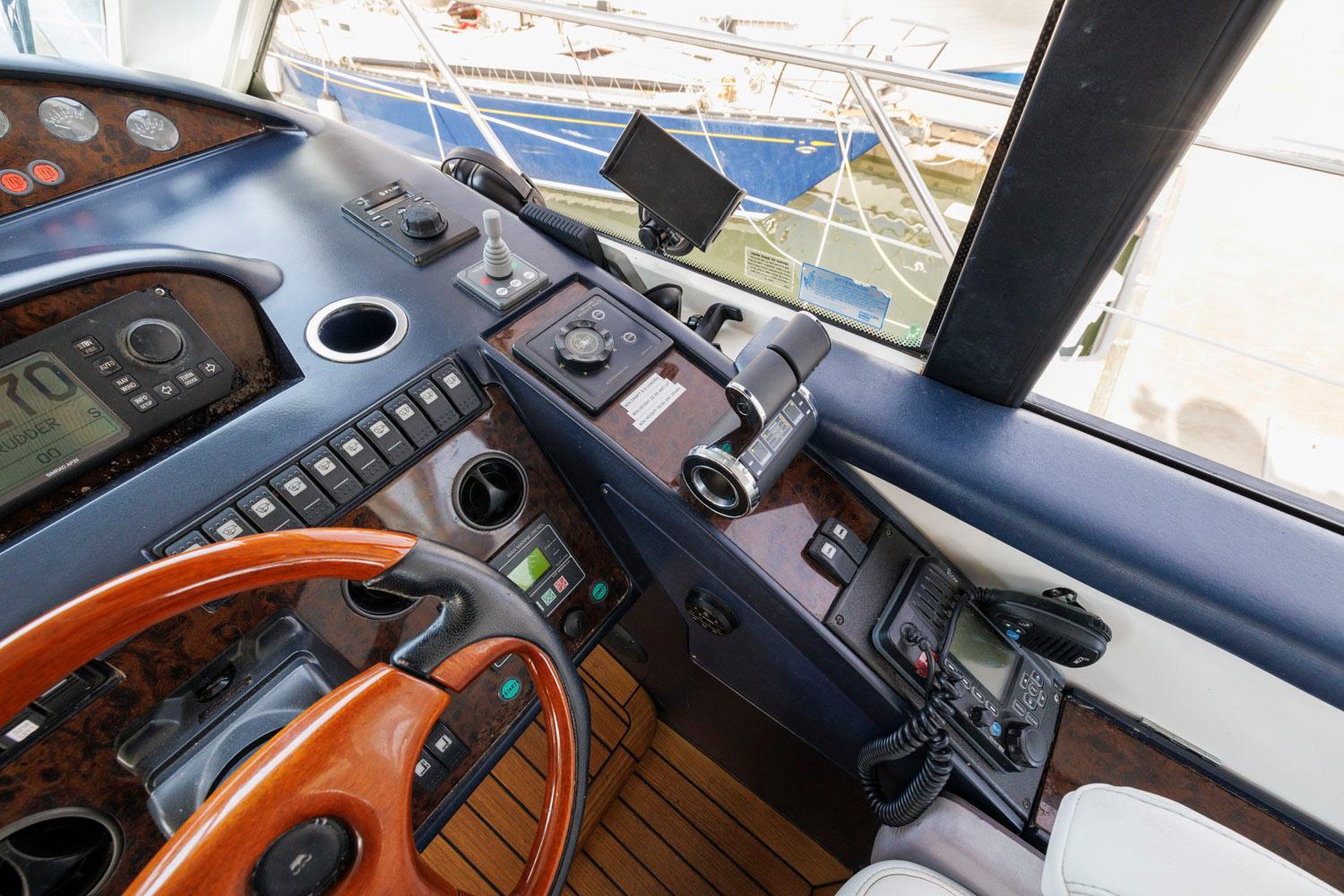 Princess-65 2003-DISMISSED CA-US-Control panel of a 2003 Princess 65 yacht with navigation instruments and wooden steering wheel.-8801006 | Thumbnail