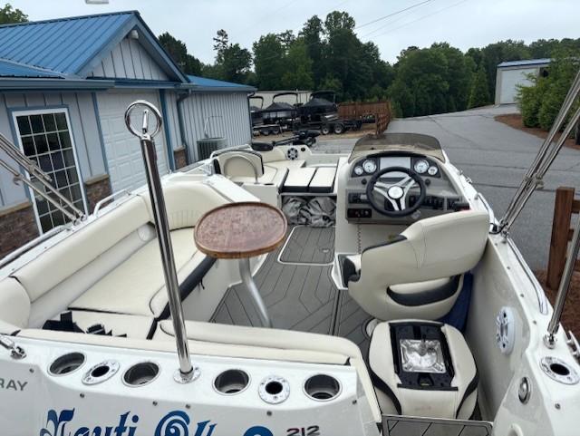 2021 Stingray 212 SC boat interior with seating, steering wheel, and table, parked near buildings.