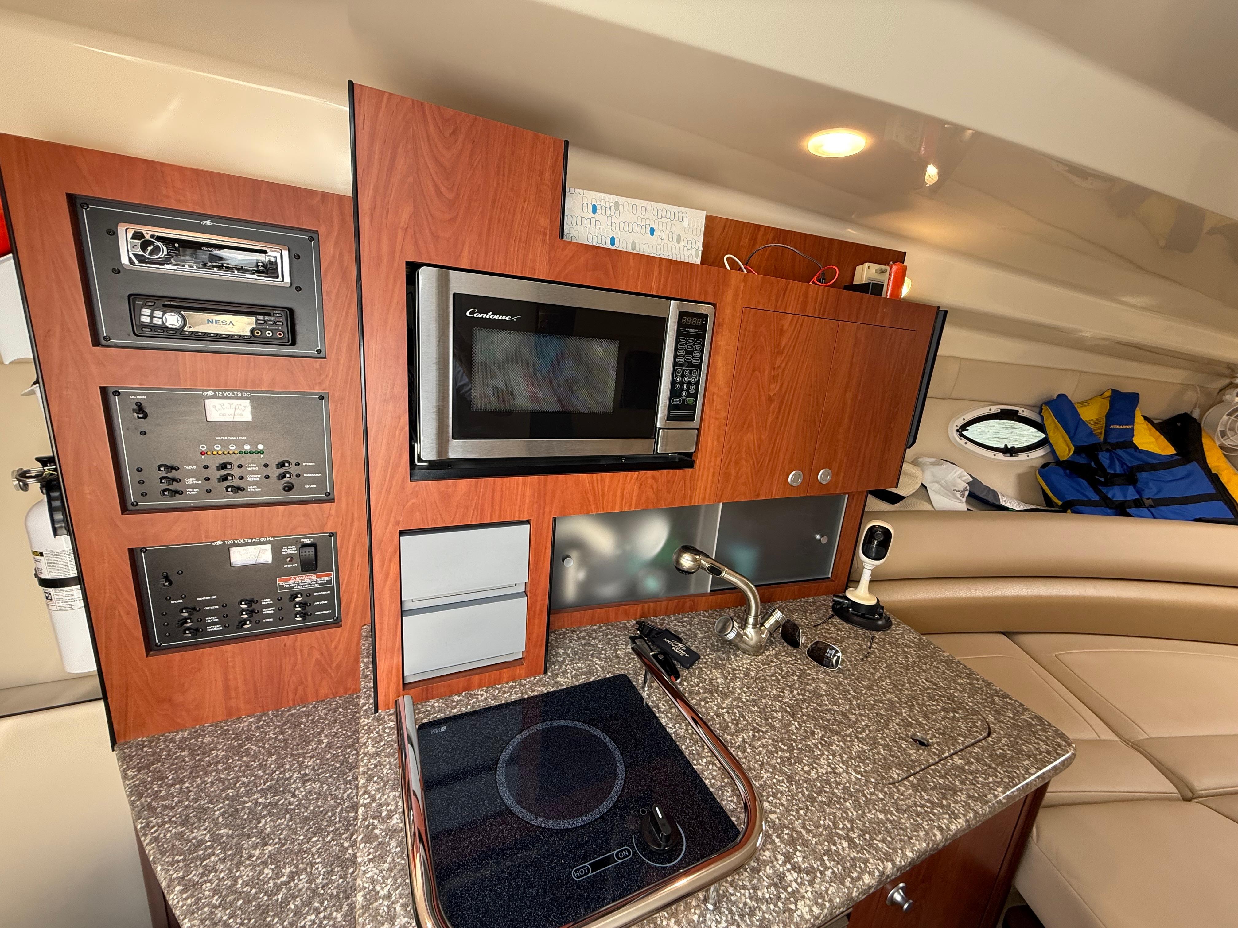 2009 Monterey 280 SCR yacht interior with kitchenette, featuring microwave, stove, and control panels.