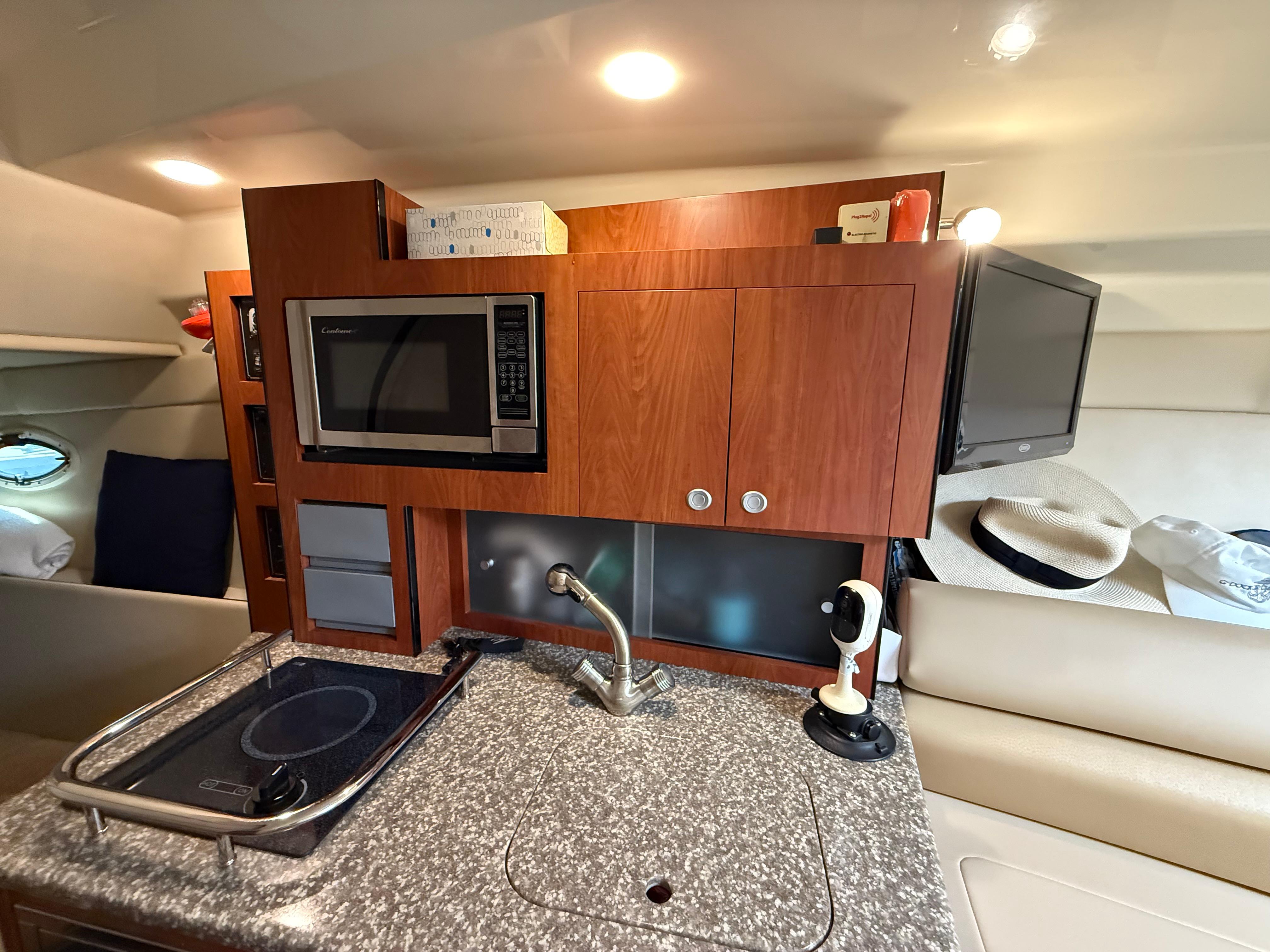 2009 Monterey 280 SCR yacht interior with kitchenette, featuring microwave, stove, and TV.