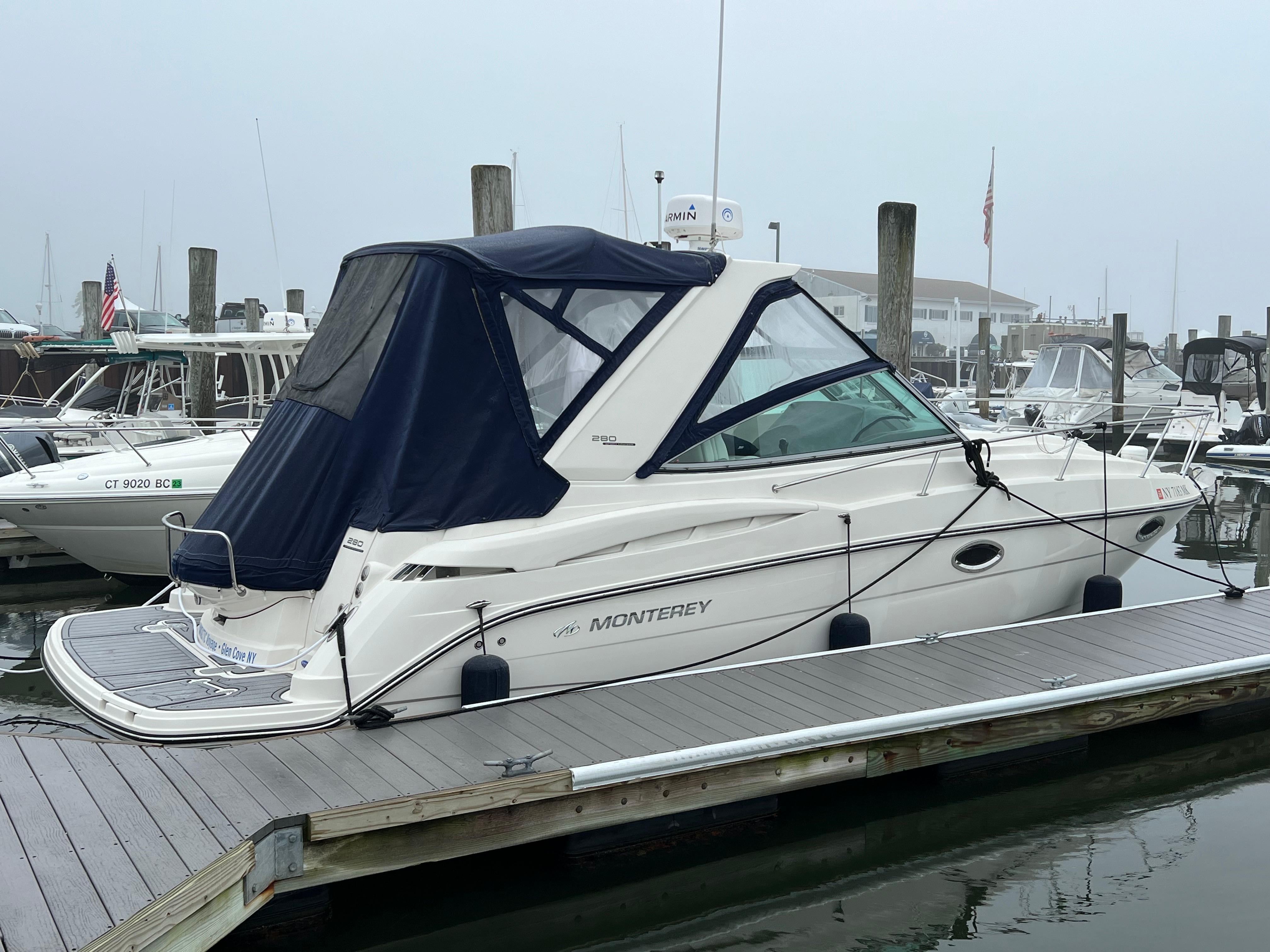 2009 Monterey 280 SCR boat docked at marina with blue canopy.