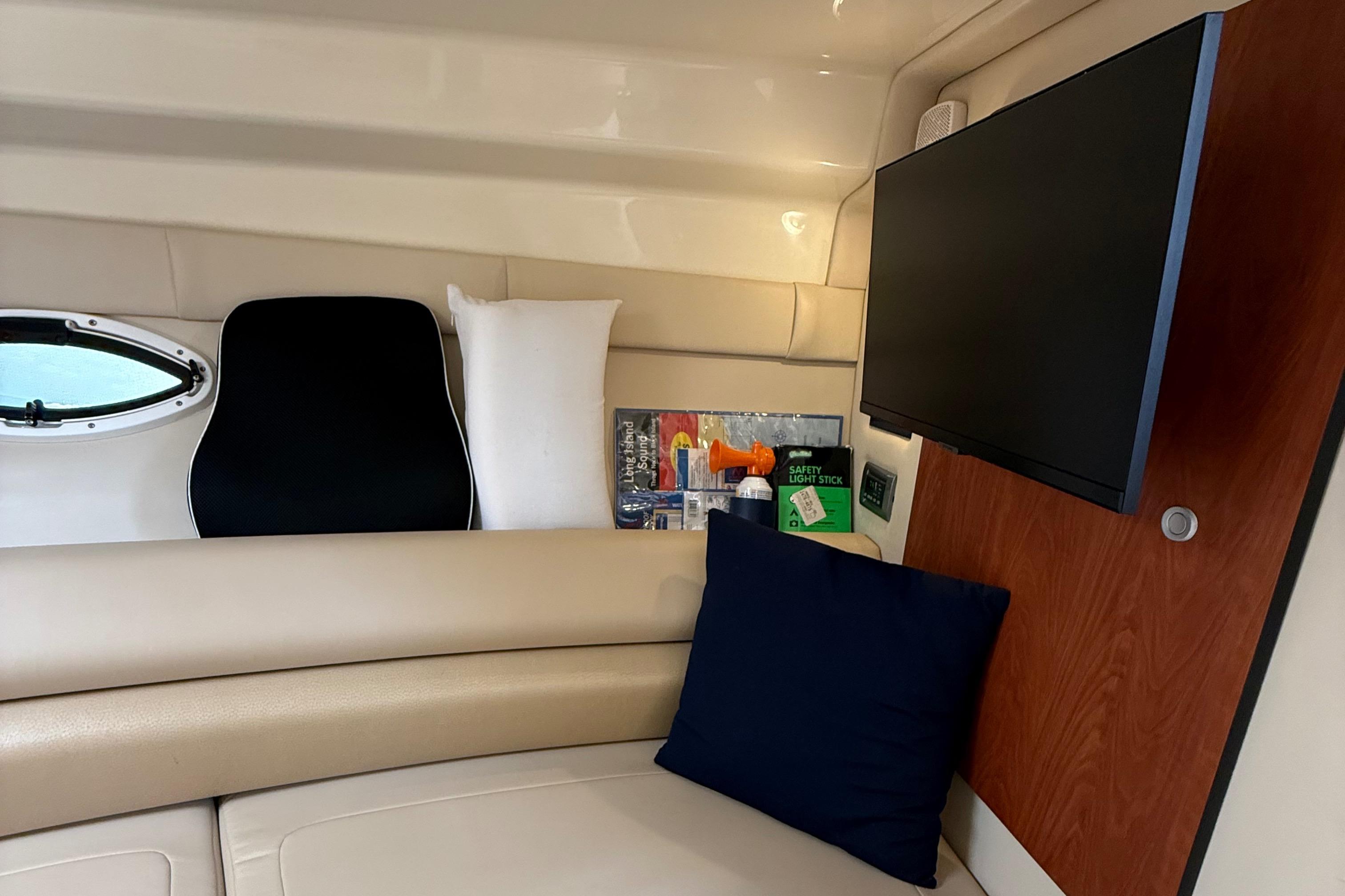 Interior of 2009 Monterey 280 SCR boat with TV, cushions, and safety equipment.