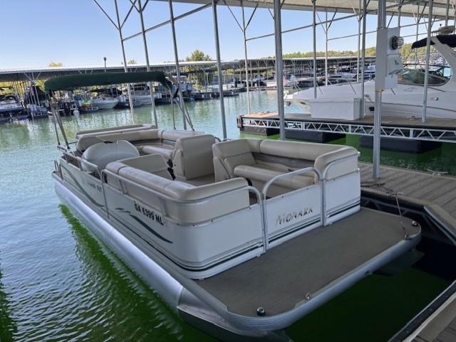 2001 Monarch 240 pontoon boat docked in a marina with green water.