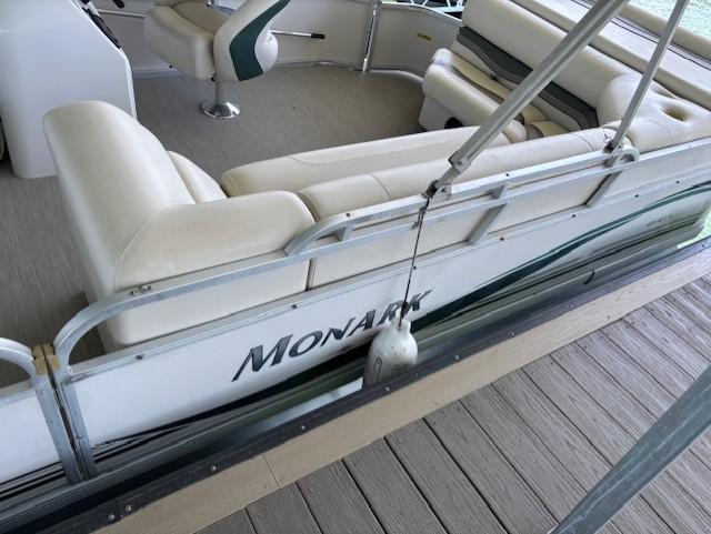 Pontoon boat Monarch 240, 2001 model, docked with beige seating and railing.